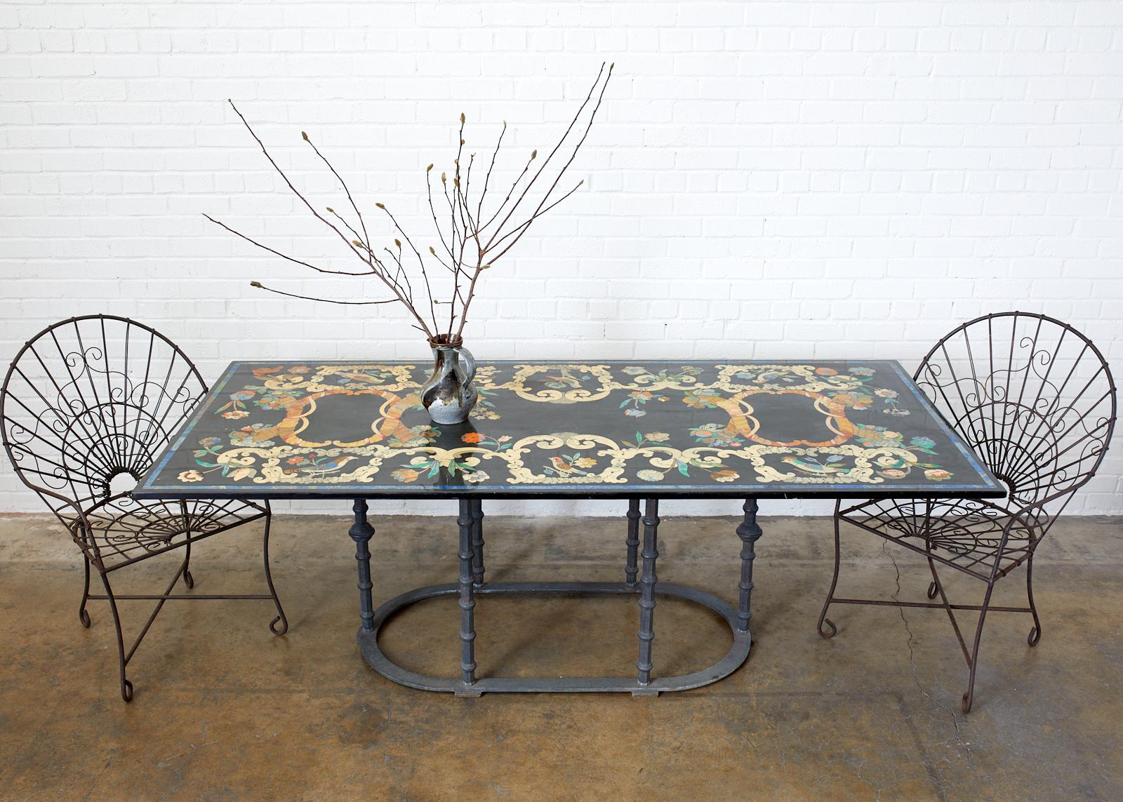 Dramatic Italian Florentine garden table or dining table featuring a handcrafted Scagliola marble top decorated with neoclassical motif inlay. The heavy slab top is nearly 1 inch thick and is supported by a heavy oval iron base. The base was custom