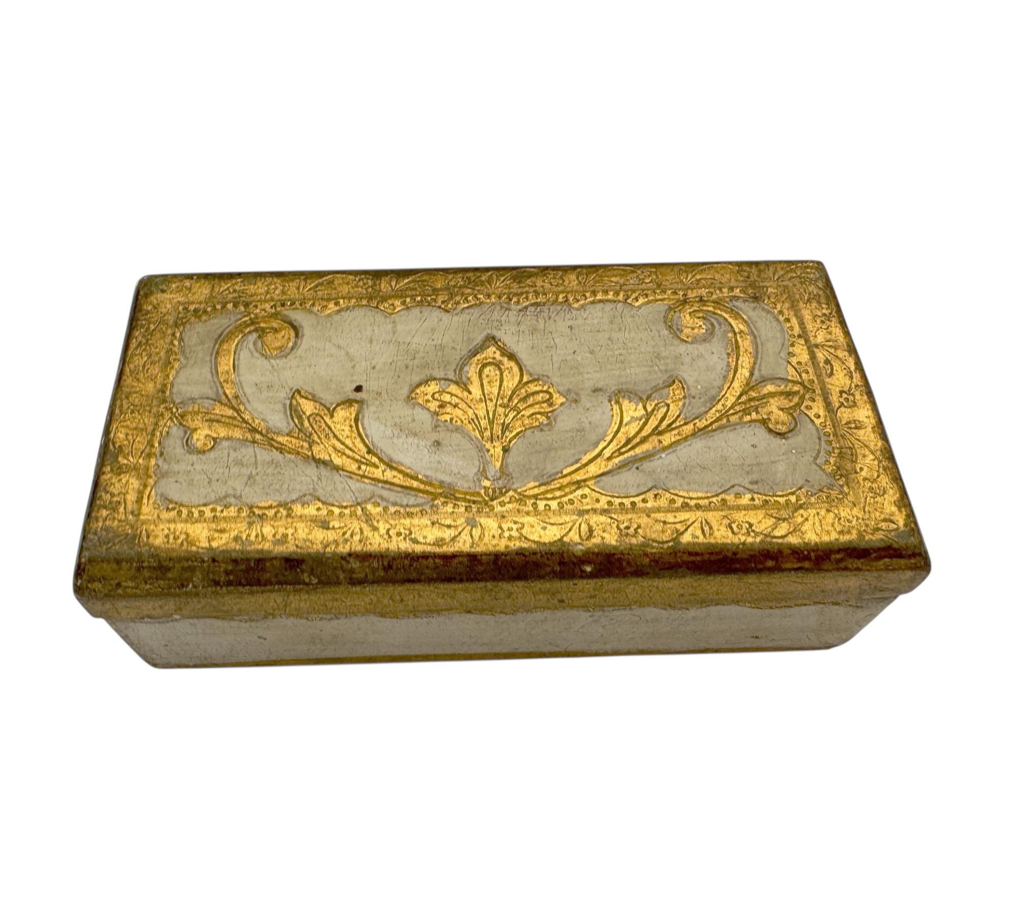 Un coffret en bois peint à la main en Italie, orné de feuilles d'or traditionnelles et de douces nuances d'ivoire. Conçu pour contenir des timbres ou d'autres petits trésors, il est orné de volutes florentines classiques et présente une patine usée