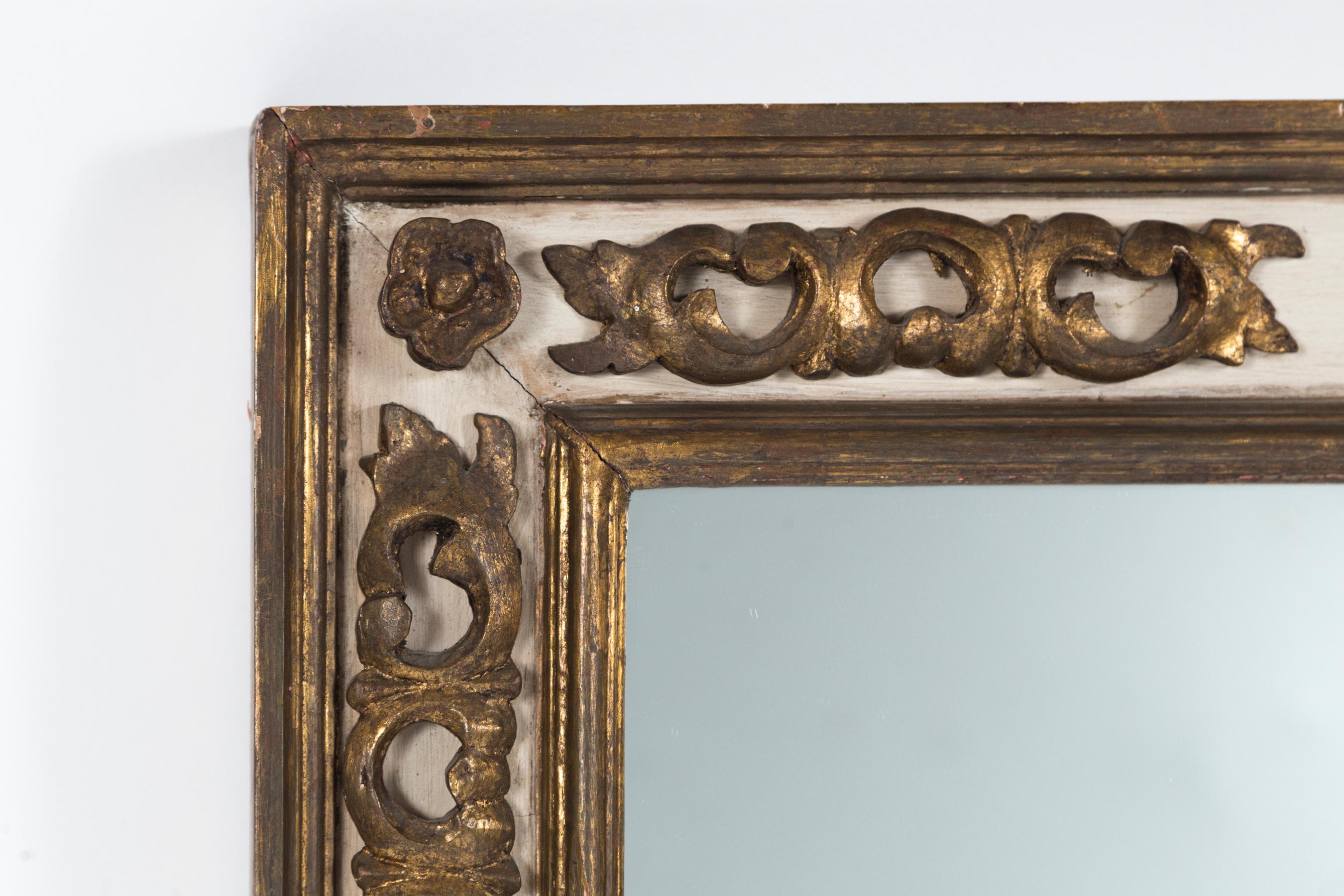 Florentine style gilded mirror, mid-20th century. Carved and gilded floral design on off-white painted panels within double moldings. Large, rectangular size frame with lovely burnished patina.