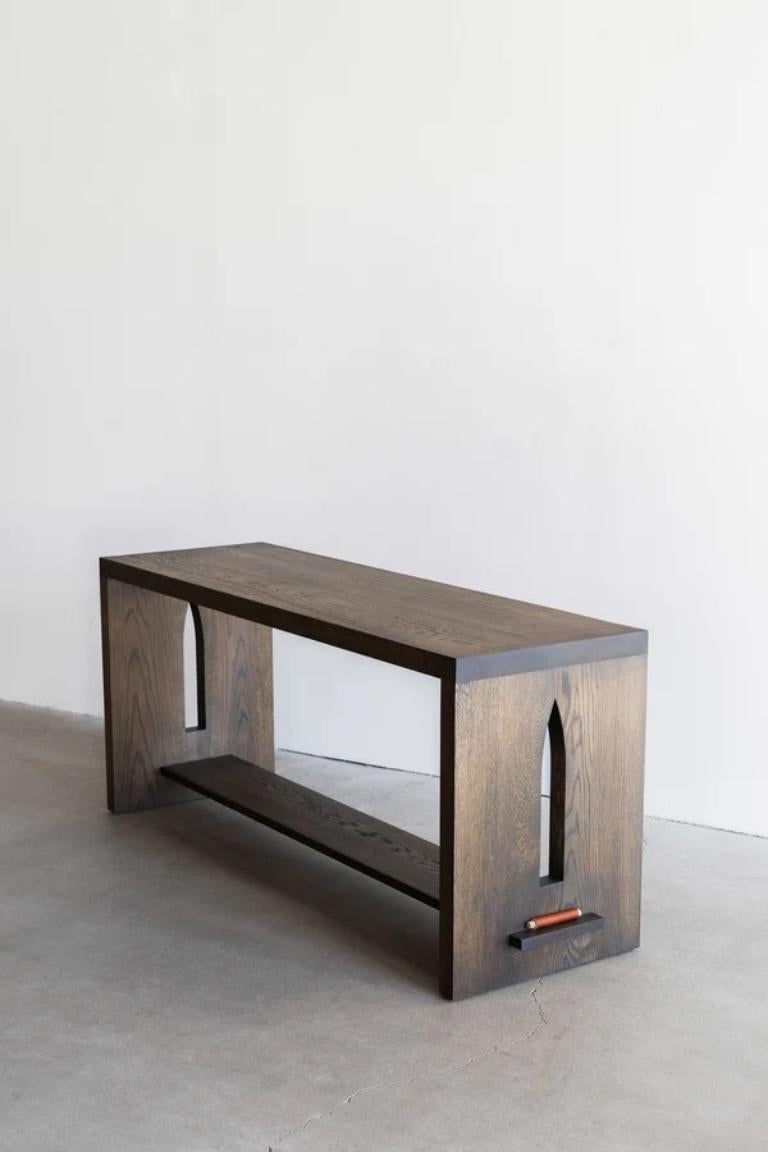 La console Flore est fabriquée en chêne massif avec une teinte riche et foncée. Les détails définissent la pièce. Elle présente des découpes en forme de clocher dans les montants de bois, rappelant les petites églises de style espagnol qui parsèment