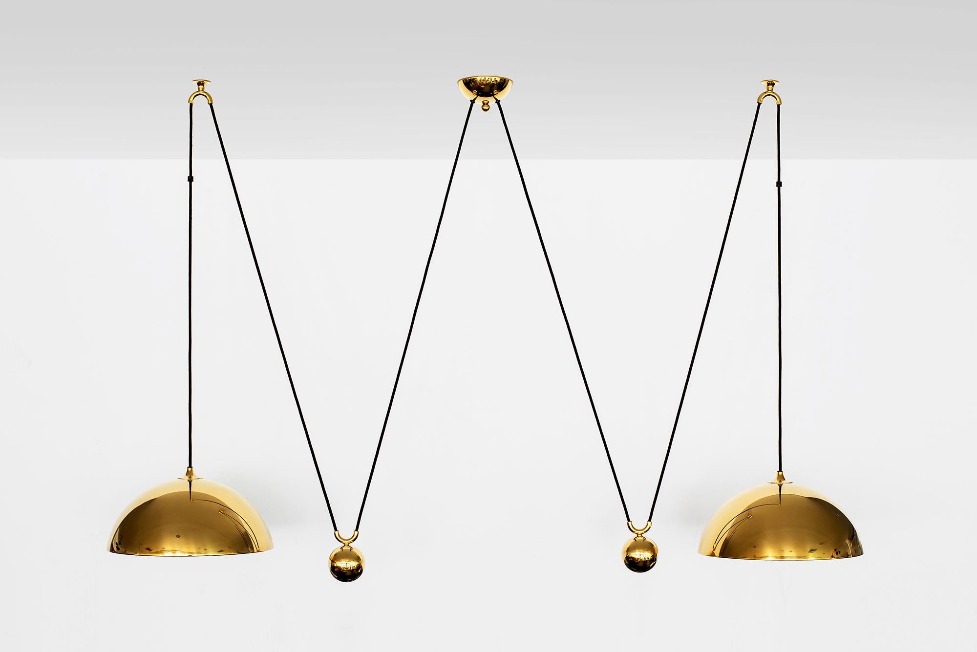 Double brass dome counterbalance pendant by Florian Schulz. 
Two brass pendants suspended, each with their own brass ball counter balance pulley system. 
One center canopy supports both pendants. Each light is adjustable in height without