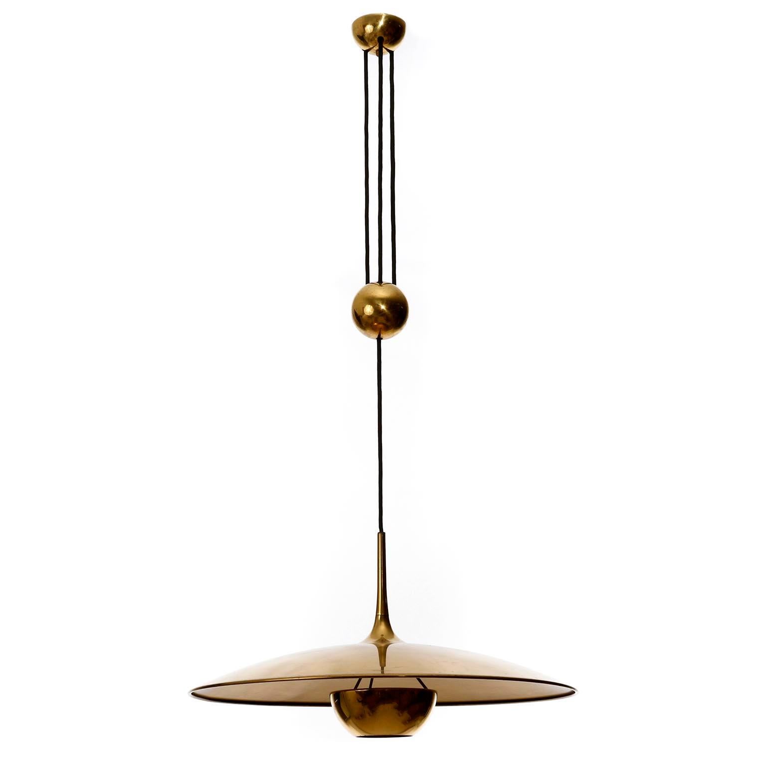 A height adjustable pendant lamp by Florian Schulz, Germany, manufactured in midcentury, circa 1970 (late 1960s-early 1970s).
The fixture is made of solid brass with a polished and aged surface in a rich and warm tone with patina and little wear of