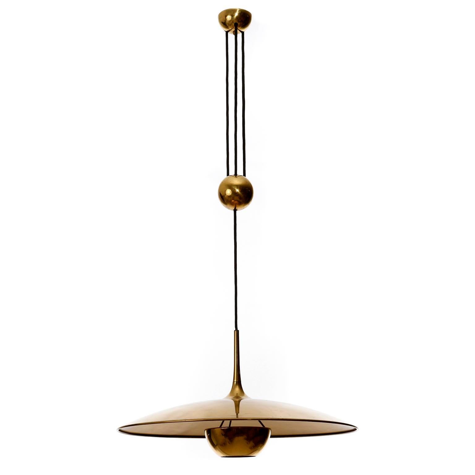 One of three height adjustable pendant lamps by Florian Schulz, Germany, manufactured in midcentury, circa 1970 (late 1960s-early 1970s).
The fixture is made of solid brass with a polished and aged surface in a rich and warm tone with patina and