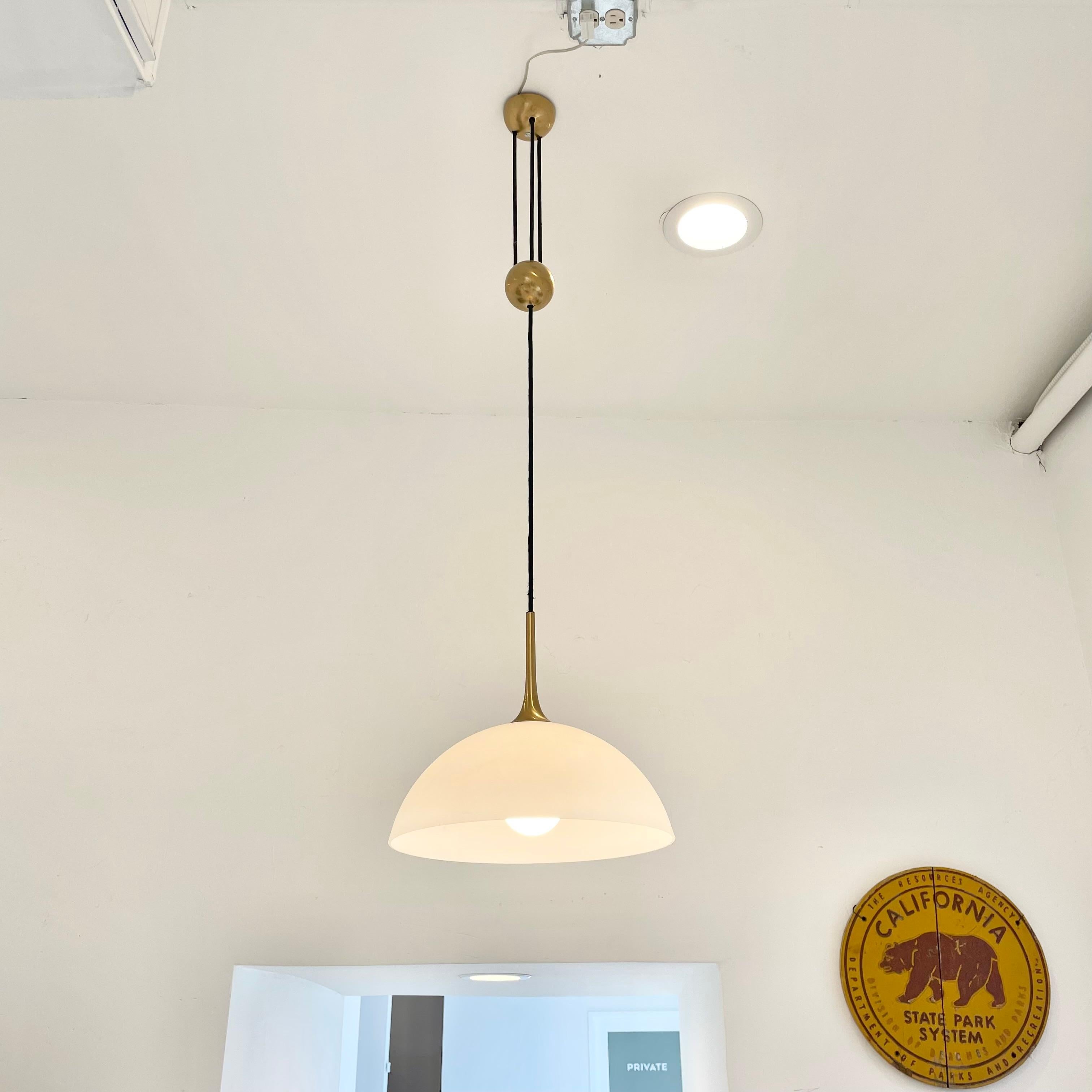 Rare counter balance pendant by Florian Schulz. Beautiful brass canopy feeds three black cloth cords with a centered brass counter balance ball. Frosted glass shade can be pulled down or pushed up to shorten or extend the length of the pendant