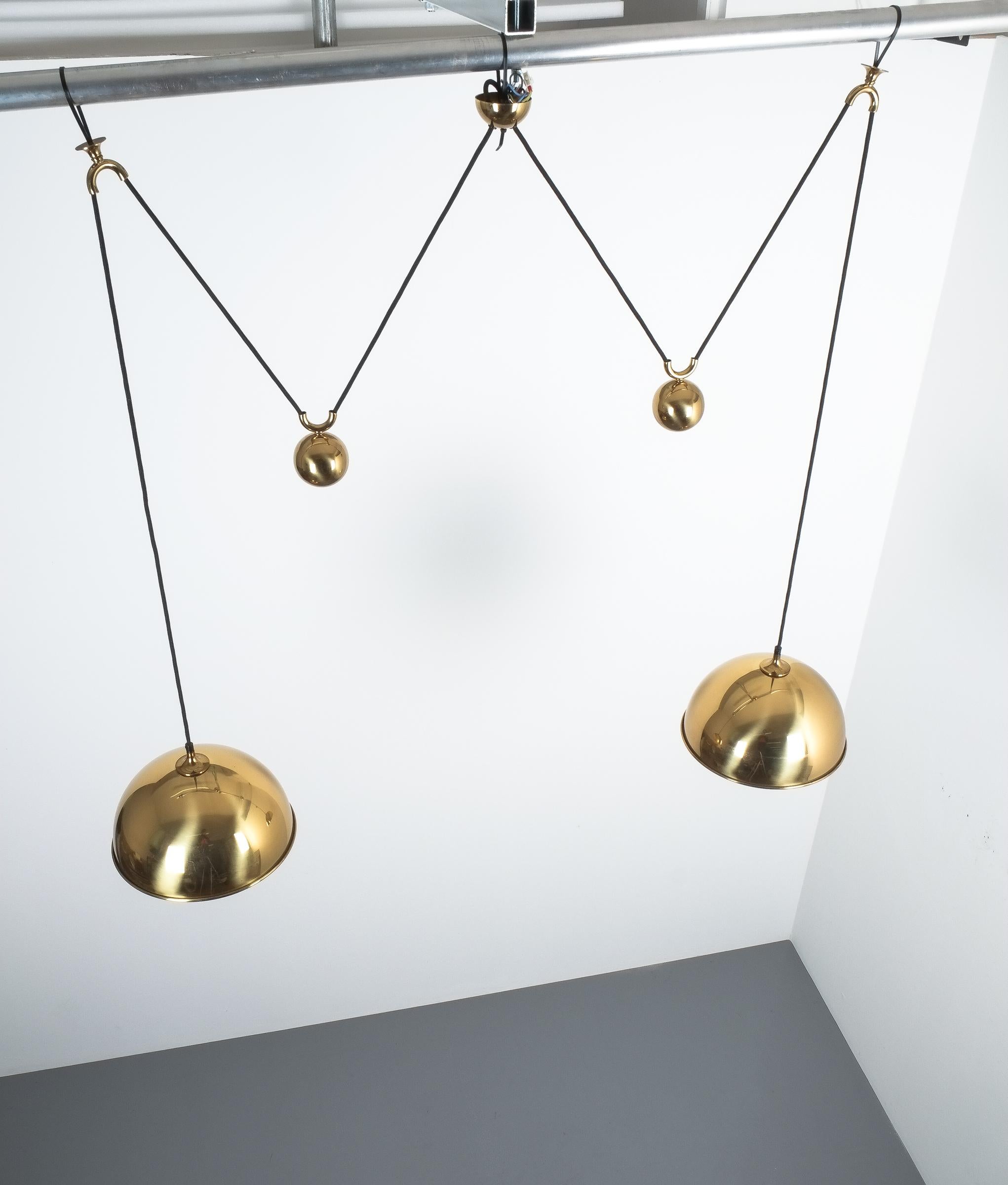 Elegant double counter balance pendant by Florian Schulz, Germany with a polished brass finish and heavy counterweights to easily adjust the light in height. Each light is adjustable in height without affecting the other. Excellent condition, it