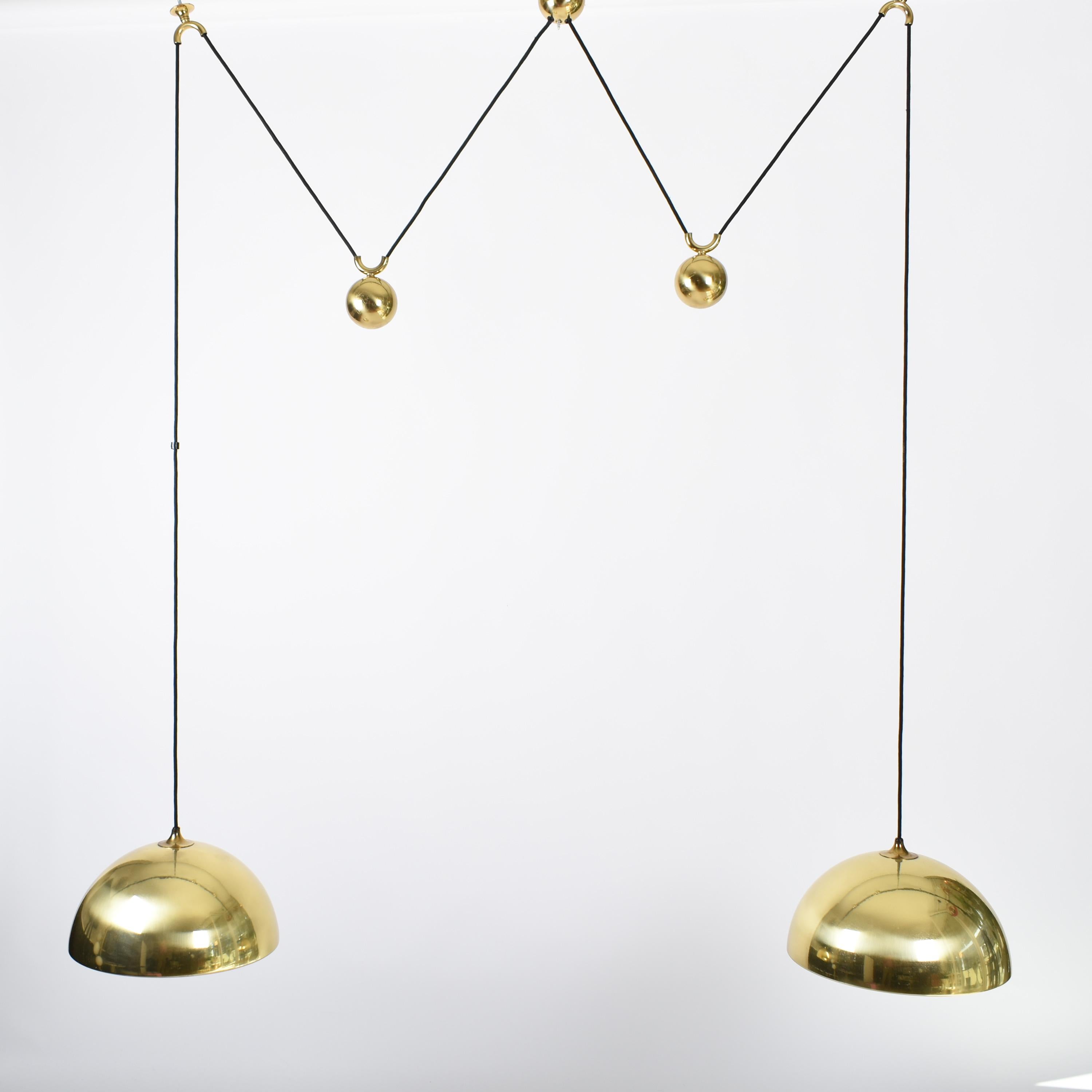 Brass counterbalance pendant lamp by Florian Schulz. 
Two brass pendants suspended, each with their own brass ball counter balance pulley system. 
Each light is adjustable in height without effecting the other. 
Pendants are connected with black