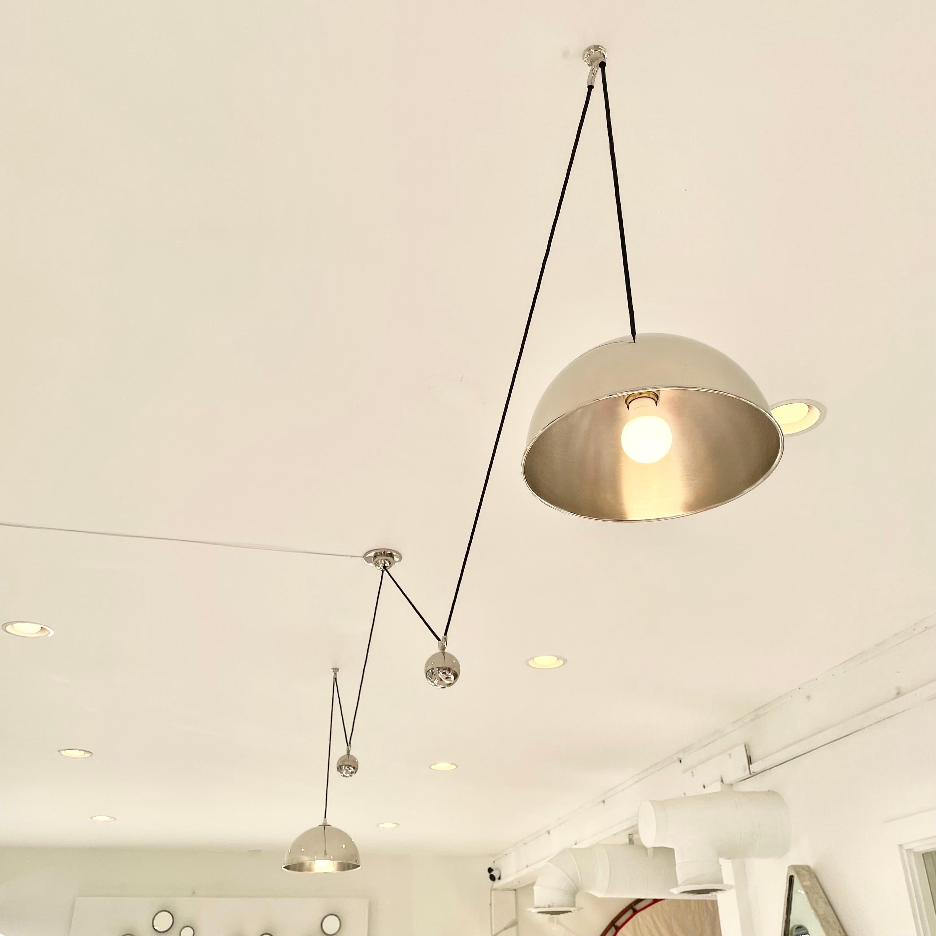 Architectural nickel counter balance chandelier by Florian Schulz. Two pendants hang on both sides of a center canopy. Nickel counter weights, canopy and hardware. Pendants are height adjustable simply by pulling down or pushing up on each light.