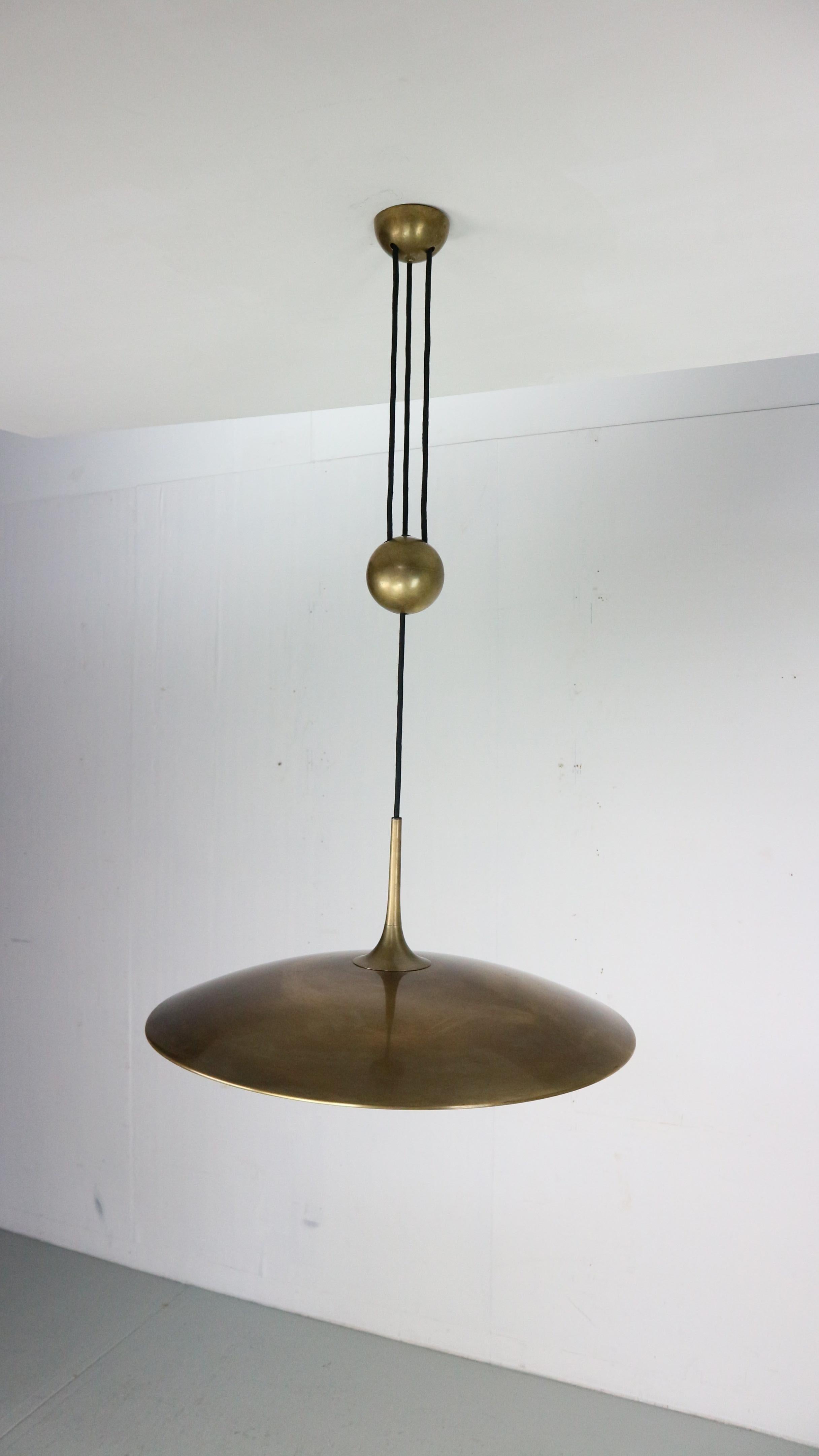 A height adjustable counter weight / balance pendant lamp by Florian Schulz, Germany, manufactured in midcentury, circa 1960 (late 1960s-early 1970s).
The fixture is made of solid brass with a natural aged and patinated surface in a rich and warm