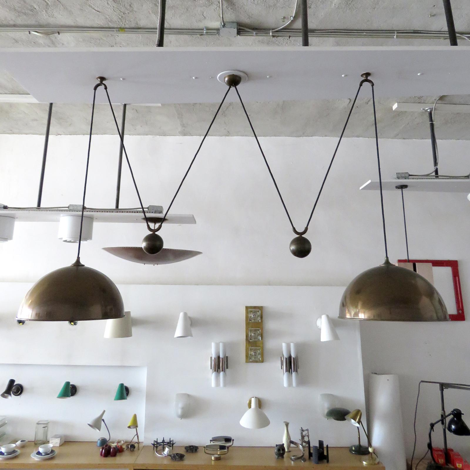 Stunning double brass counter balance pendant by Florian Schulz in great vintage condition, with two brass pendants suspended, each with their own very heavy brass ball counter balance pulley system and black cloth cord, supported by a single center