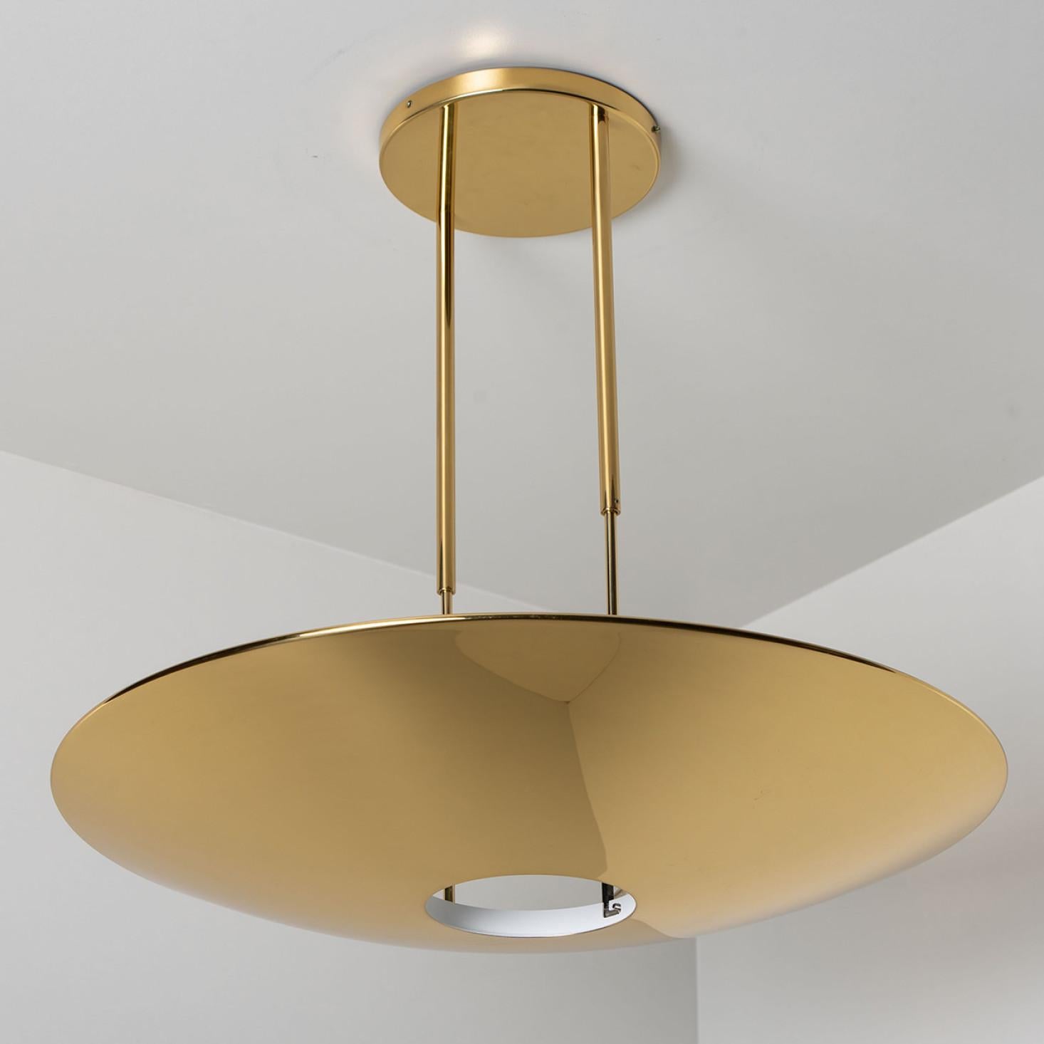 High quality brass pendant lamp or ceiling fixture 'Sola 80' by Florian Schulz. The light has an opening at the bottom for a round diffuser out of glass. It is 90 cm in diameter and radiates a direct and an indirect lighting.
The light is adjustable