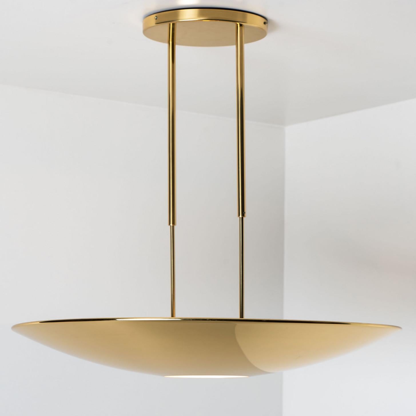 High quality brass pendant lamp or ceiling fixture 'Sola 80' by Florian Schulz. The light has an opening at the bottom for a round diffuser out of glass. It is 90 cm in diameter and radiates a direct and an indirect lighting.
The light is adjustable