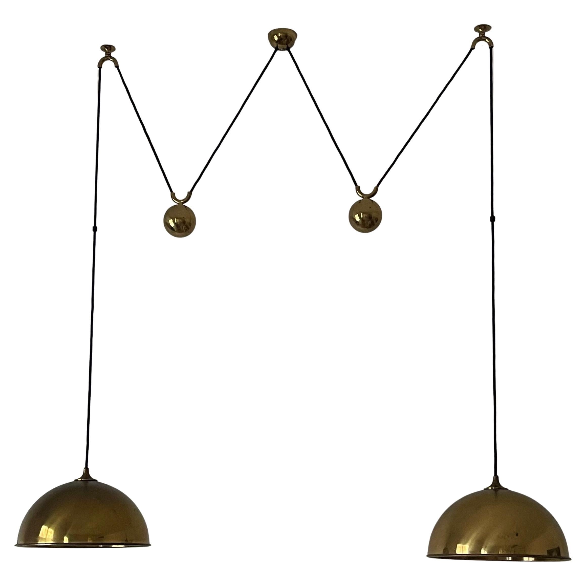 Double polished brass counterbalance pendant by Florian Schulz. Two brass pendants suspended, each with their own brass ball counter balance pulley system. One centre canopy supports both pendants. Each light is adjustable in height without