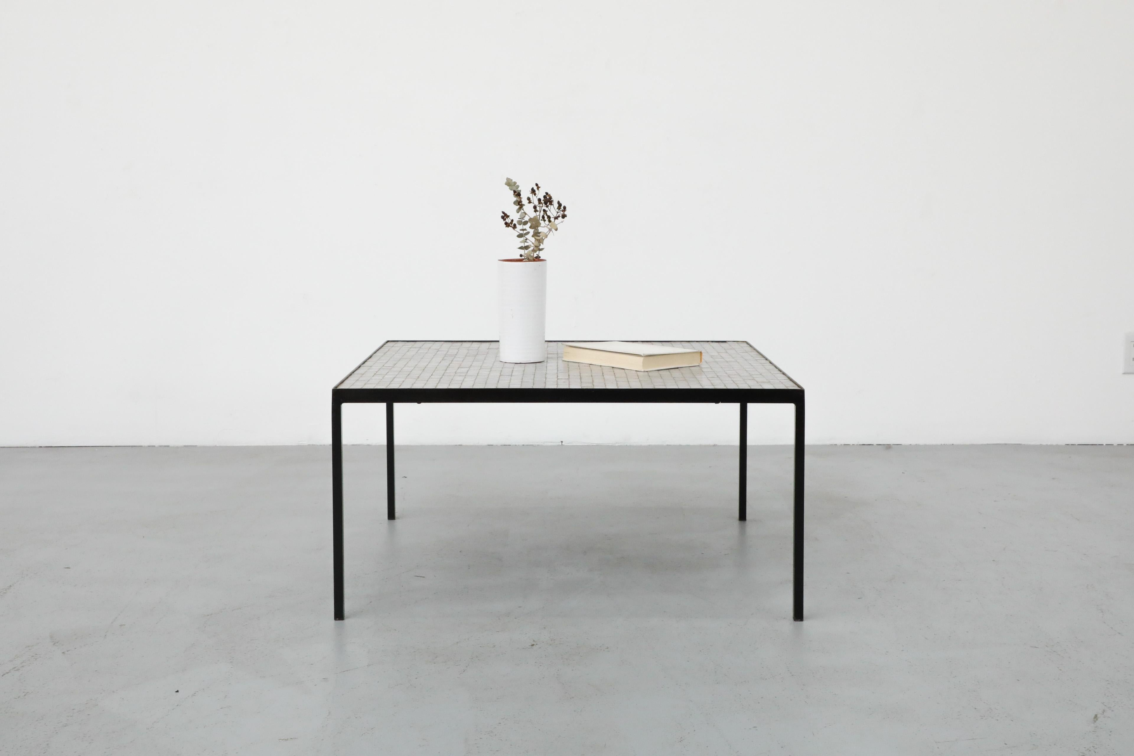 Gorgeous square black enameled metal coffee table with inset glass mosaic tile by Floris Fiedeldij for Artimeta. A mid-size coffee table with small light gray, white and cream square tile top and black frame. In original condition with some visible