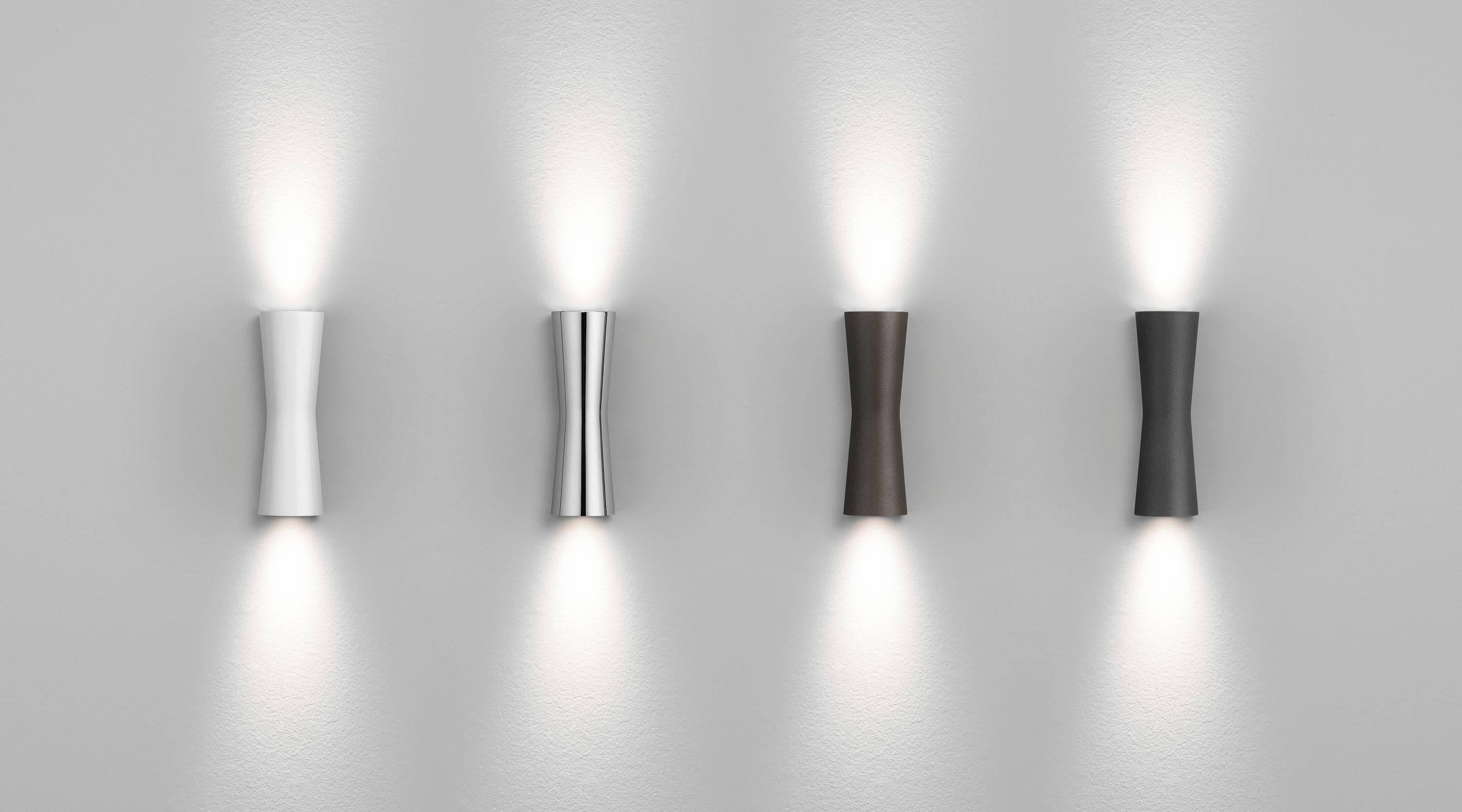 Inspirada en la forma del reloj de arena, la lámpara Clessidra de Antonio Citterio emite luz difusa directa e indirecta. Este asombroso aplique de pared tiene un cuerpo de aluminio fundido a presión con acabado pulverizado y un difusor de PMMA