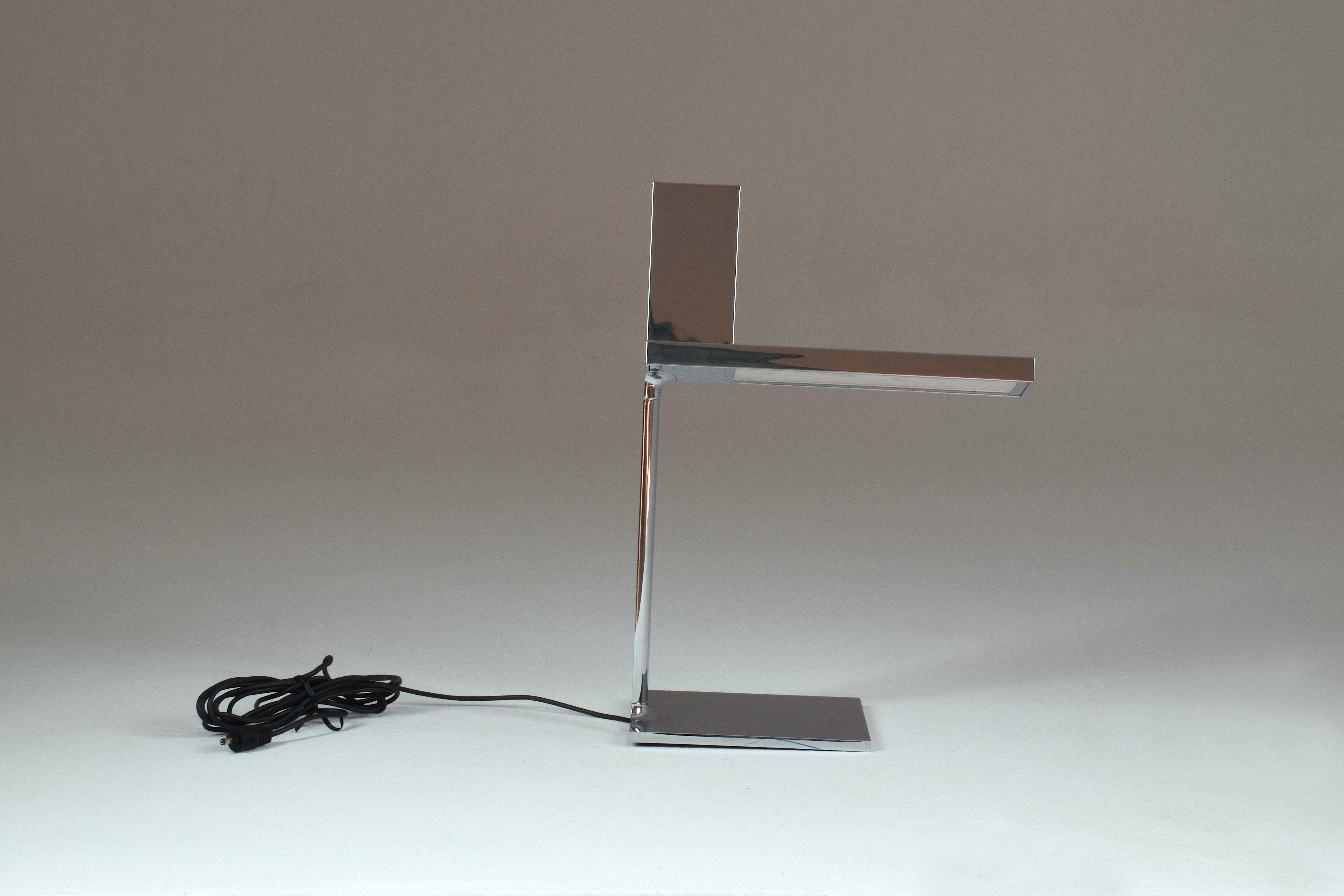La lampe d'espace de travail italienne D'e-light de Philippe Starck pour Flos présente un design épuré, moderne et multifonctionnel. Ce Design-Light dispose d'un espace sur le dessus pour ranger et charger tout type d'appareil tel que téléphone,