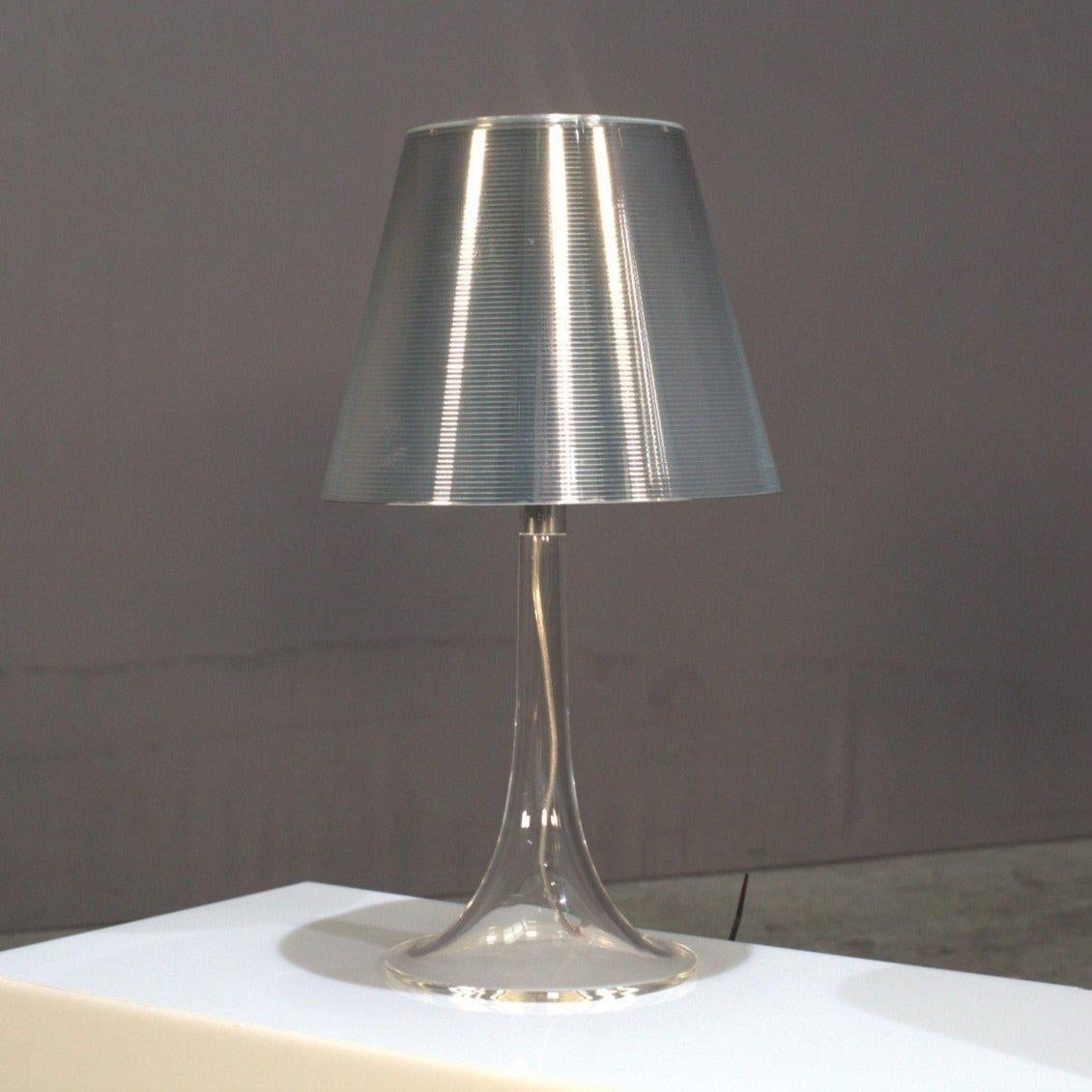 The Flos Miss K Table Lamp by Philippe Starck is a contemporary masterpiece that effortlessly combines elegance with functionality. Its iconic design features a sleek, transparent outer diffuser paired with an inner shade that emits a warm, inviting