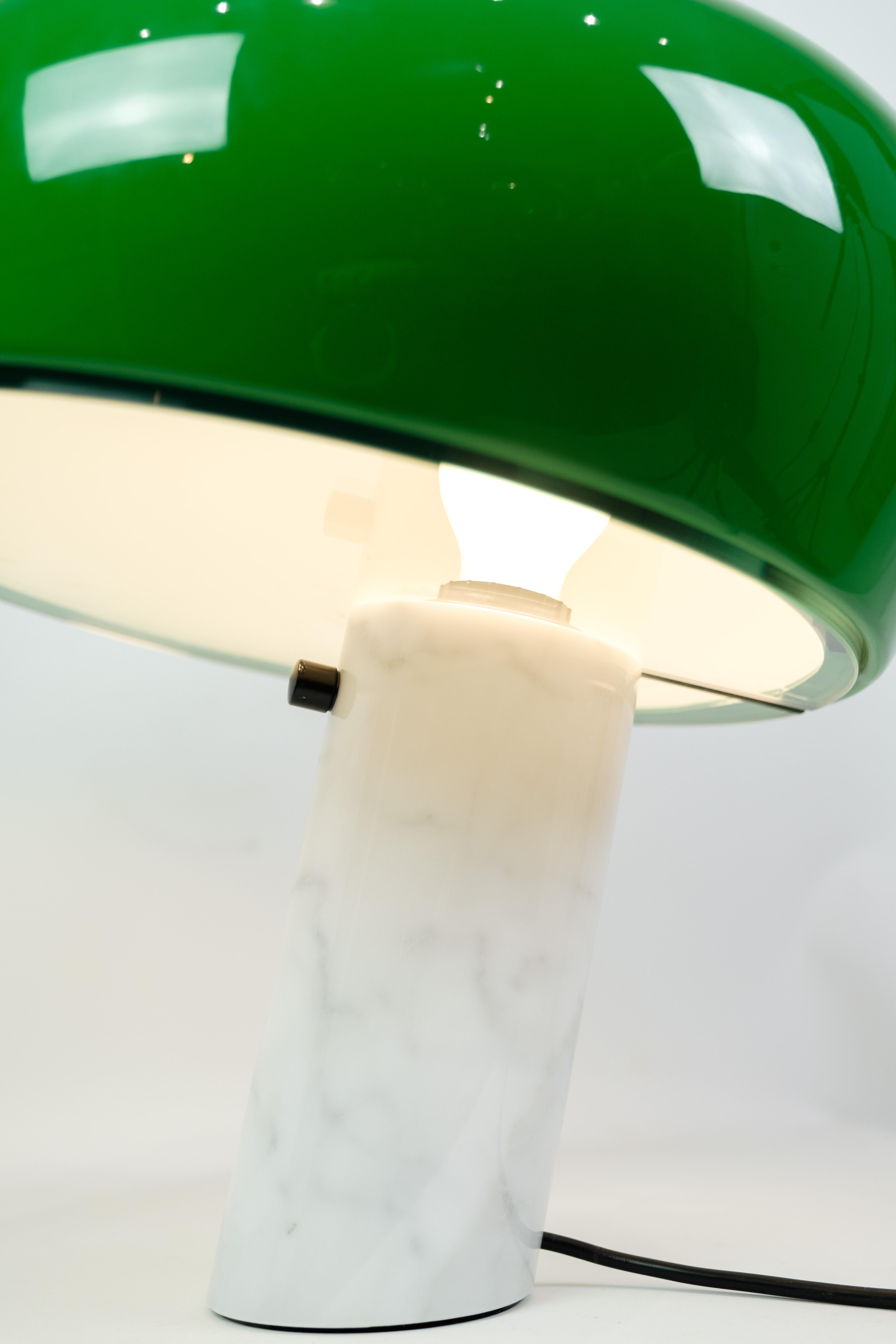 Table lamp with green enamelled metal reflector and white Carrara marble base. The lamp was designed by Achille and Pier Giacomo Castiglioni in 1967. The lamp is made by Flos and the light from the lamp creates a cozy atmosphere.
Dimensions: H:37 cm
