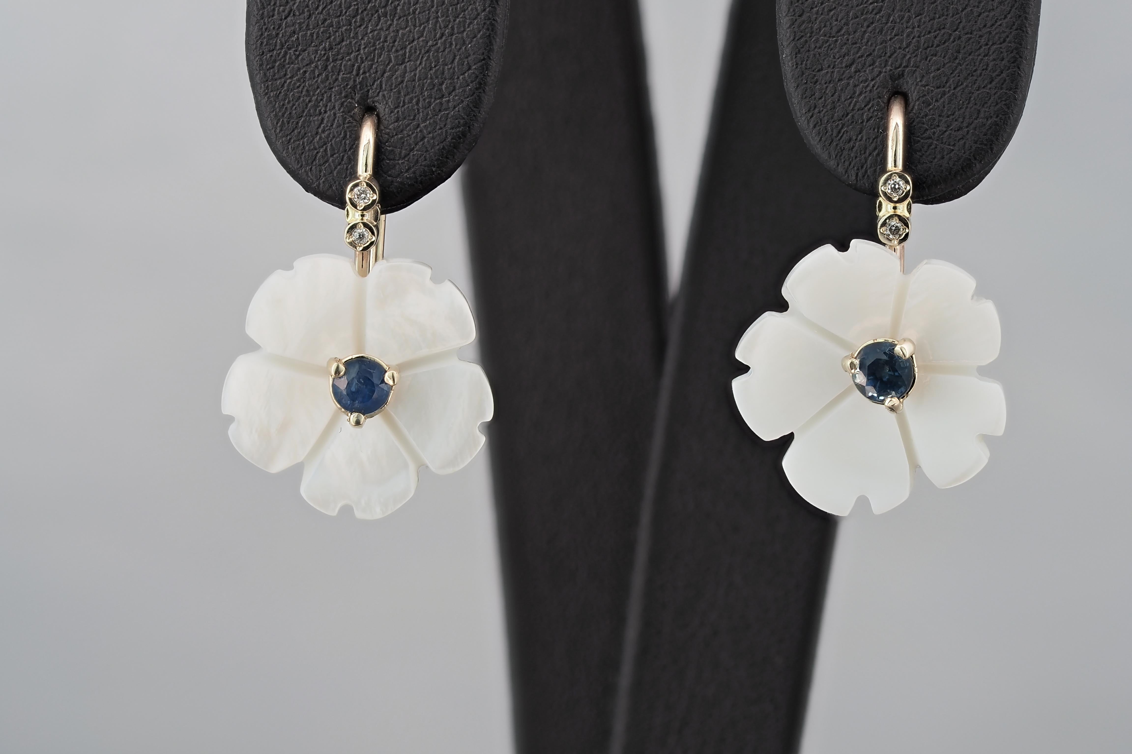 Flower 14k gold earrings with blue sapphires. 
Blue sapphires and carved mother of pearl earrings. Blue sapphires gold earrings.

Metal: 14k gold. 
Weight: 3 gr.

Central stone: Sapphires- 2 pieces 
Cut: Round  
Weight: aprx 0.25 ct. total. 
Color: