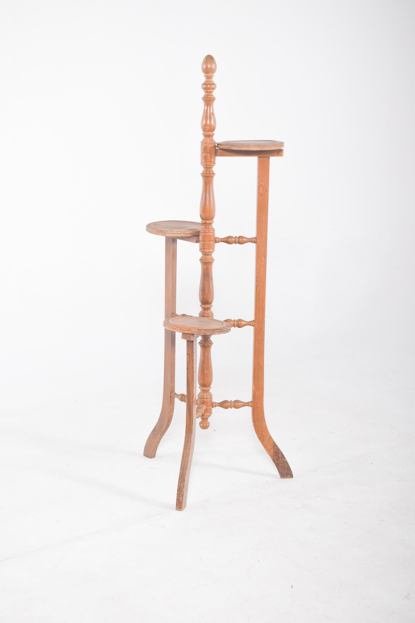 Flower box with circular supports for three pots. The structure is made up of three curved legs and turned reinforcements that connect the support levels, ensuring stability. Each shelf is arranged at different heights, creating a spiral composition