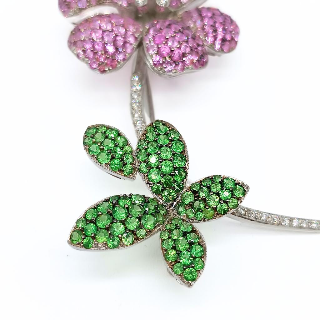 Flower Brooch 
18k White Gold 18,21gr
7 Diamonds in the center of the flower and 17 Diamonds on the branch, all in brilliant-cut 0,27k
Six Petals with 212 Pink Sapphires in round-cut 5,76k.
Five Leaves with 89 Tsavorites in round-cut 2,19k
