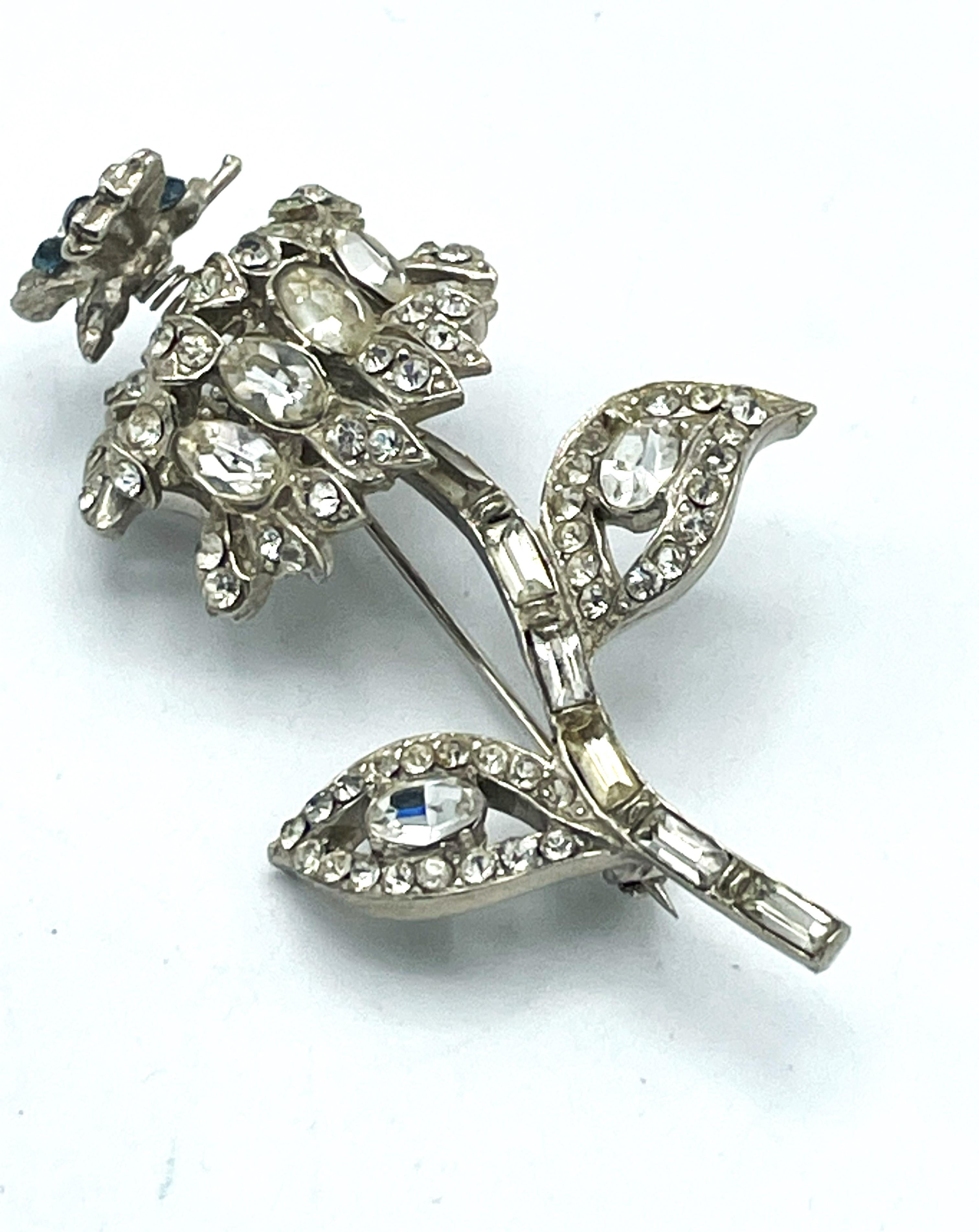 Flower brooch with a small moving butterfly on top, fully set with rhinestones, rhodium-plated metal 1940 US

Dimensions
Hight    6 cm 
Width   3.5 cm 
moving  butterfly  1 cm x 1.3 cm 