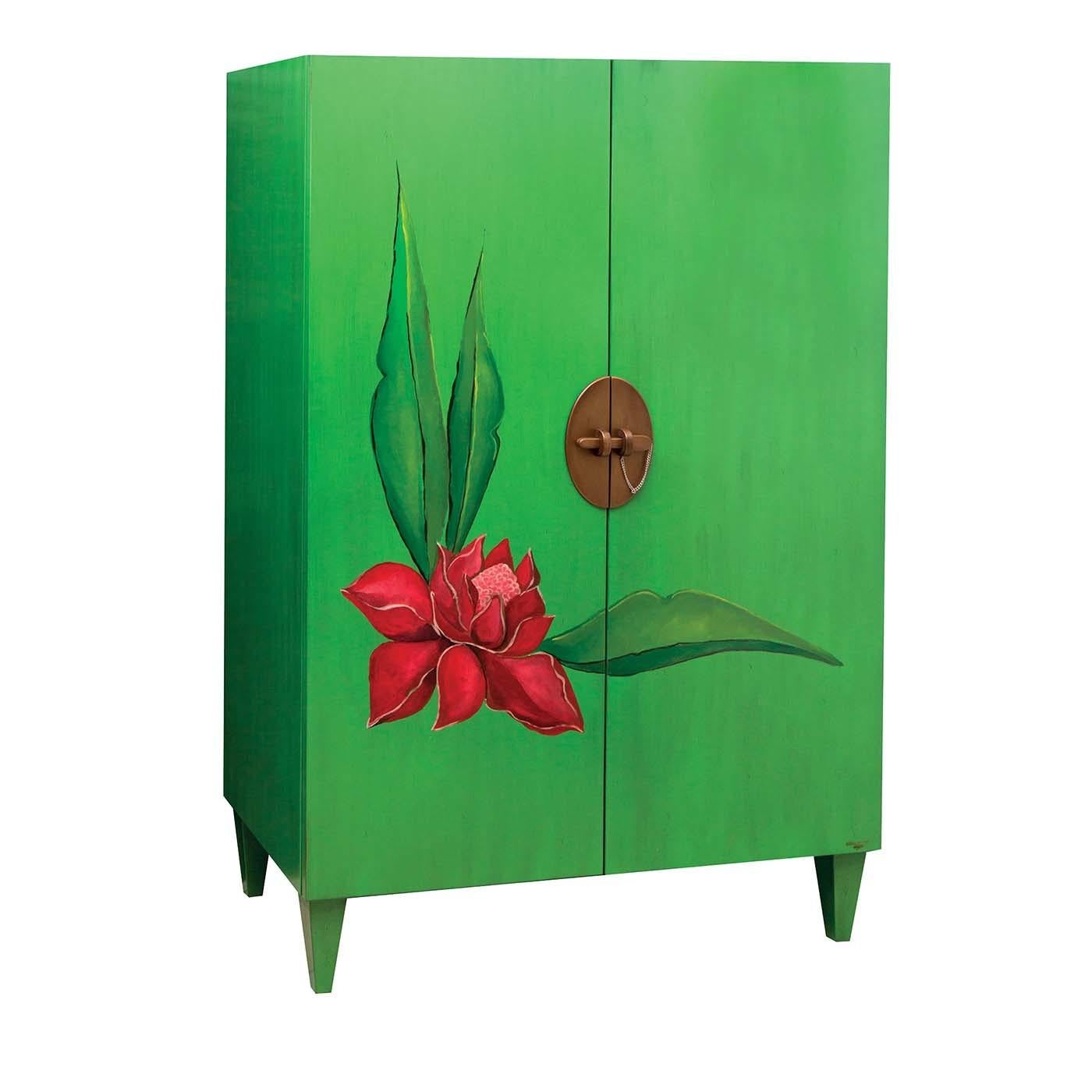 Exquisitely crafted of solid Toulipier walnut wood with Tanganica wood veneer, this cabinet will enliven the decor of a child's bedroom or an eclectic interior. Boasting a green lacquered finish enriched with an antique effect, it is adorned with a
