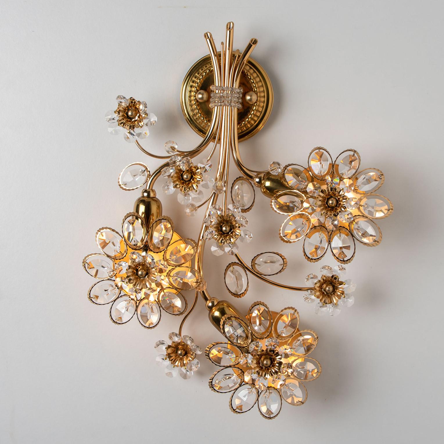 A stunning gilt and crystal wall-mounted sconce by Palwa, Germany. Manufactured around 1965-1975.
This luxurious wall light features beautifully cut crystals in the form of flowers and petals set on a gold-plated brass frame.

Measurements:
Heigth: