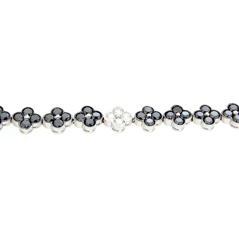 This bracelet is both elusive and dazzling with its mix of white and black diamonds. Eighteen flowers with black diamonds weighing 10.70 carats make up most of this 18K white gold bracelet. Three flowers with round cut VS quality diamonds weighing