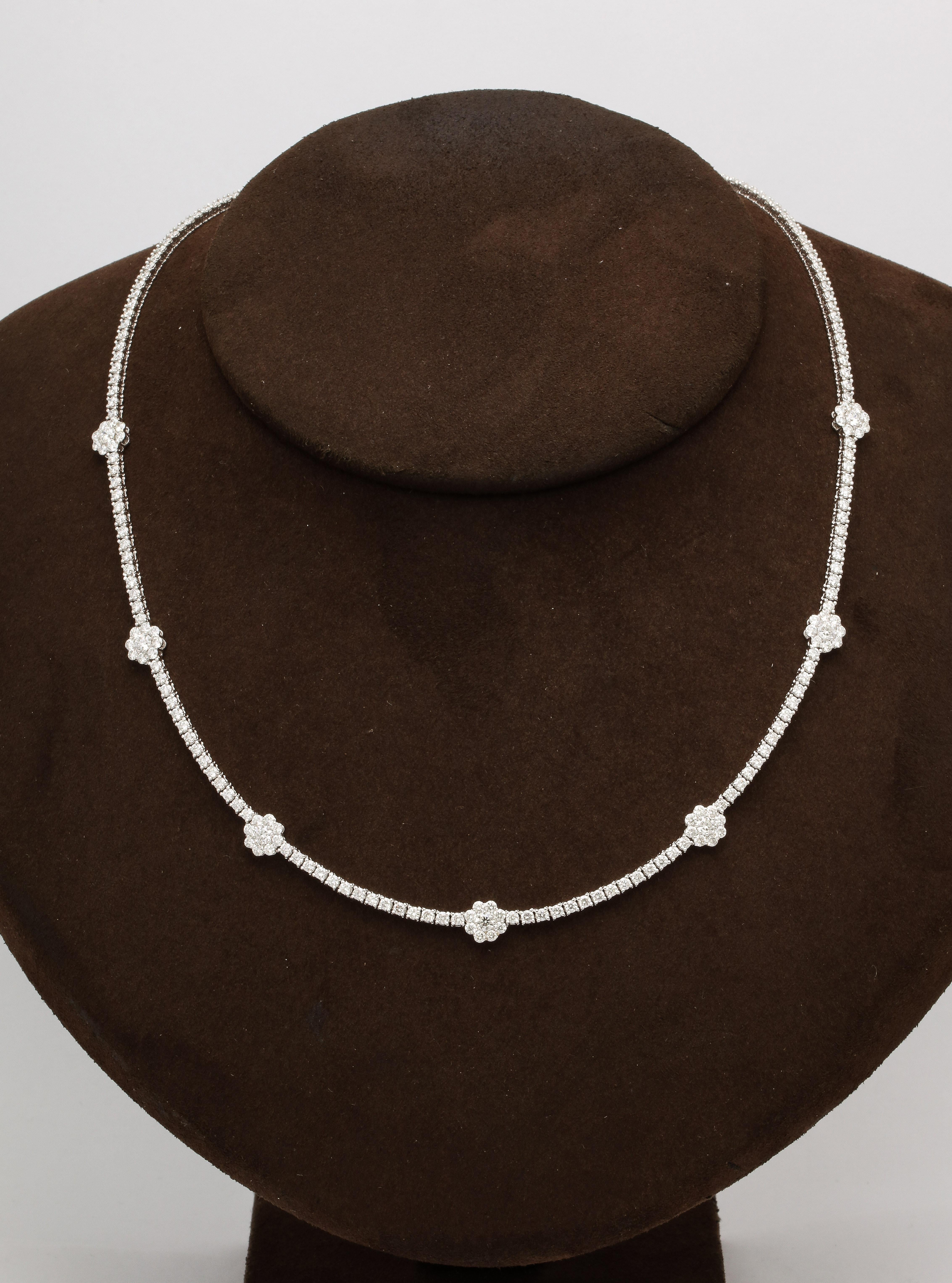 
6.75 carats of white round brilliant cut diamonds. This tennis necklace features 7 flower motifs. Set in 14k white gold. 

Looks beautiful on its own or layered with other pieces. 

17 inch length 

A matching bracelet is available in our 1stDibs