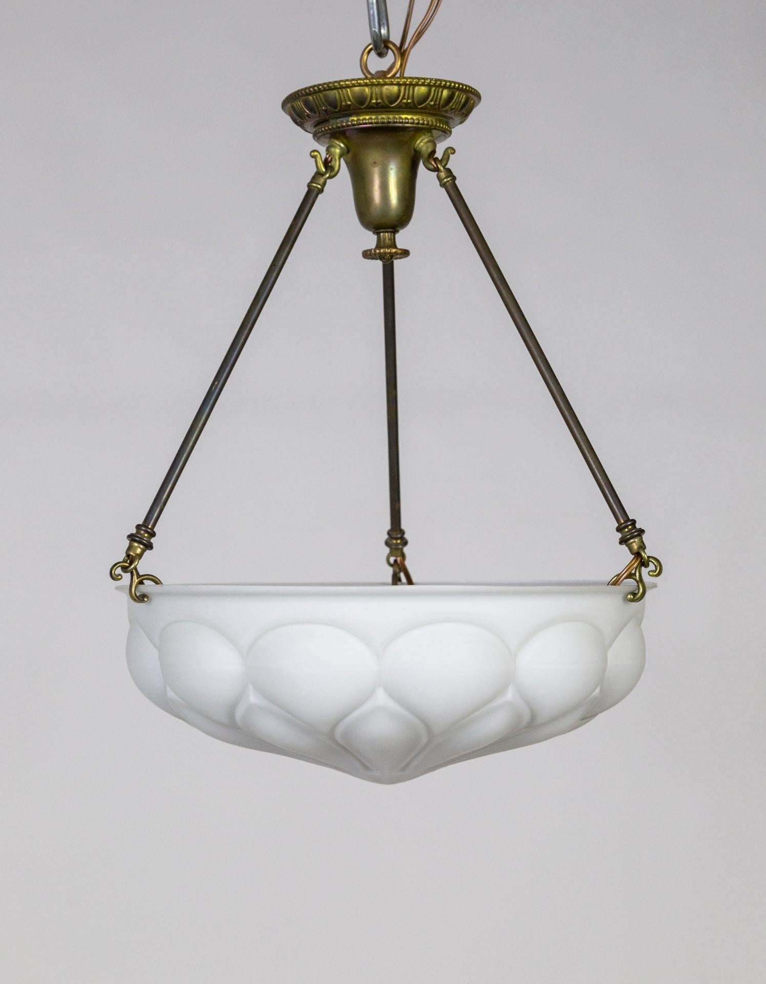 Antique, decorative, cast milk glass flower supported by gravity hooks on 3 solid brass stems. Original brass canopy, rich, antique patina. 3 medium base sockets, newly wired. When lit, the geometric pattern reveled, has a modern feel to it.