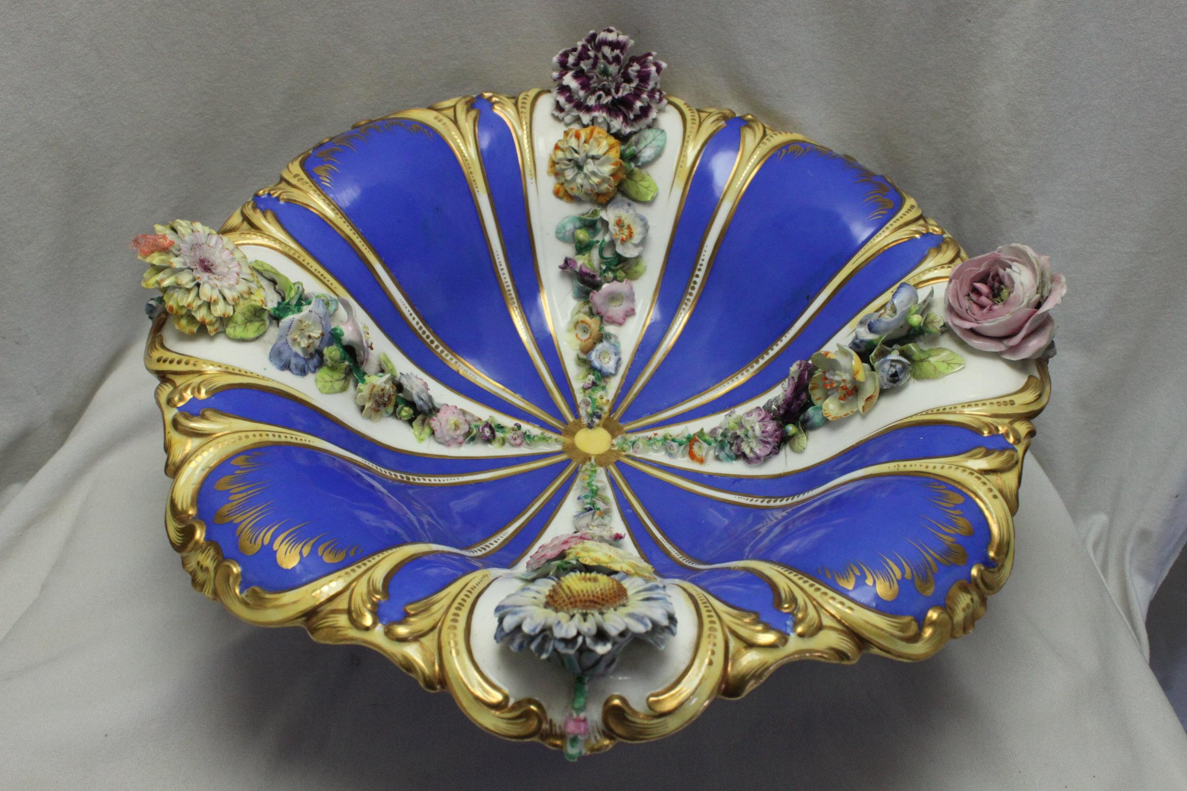 This flower encrusted ornamental bowl is attributed to Coalport. It is decorated with four lines of hand crafted flowers on the white body. These lines decrease in size towards the centre. Between each line the bowl is decorated with a ground of