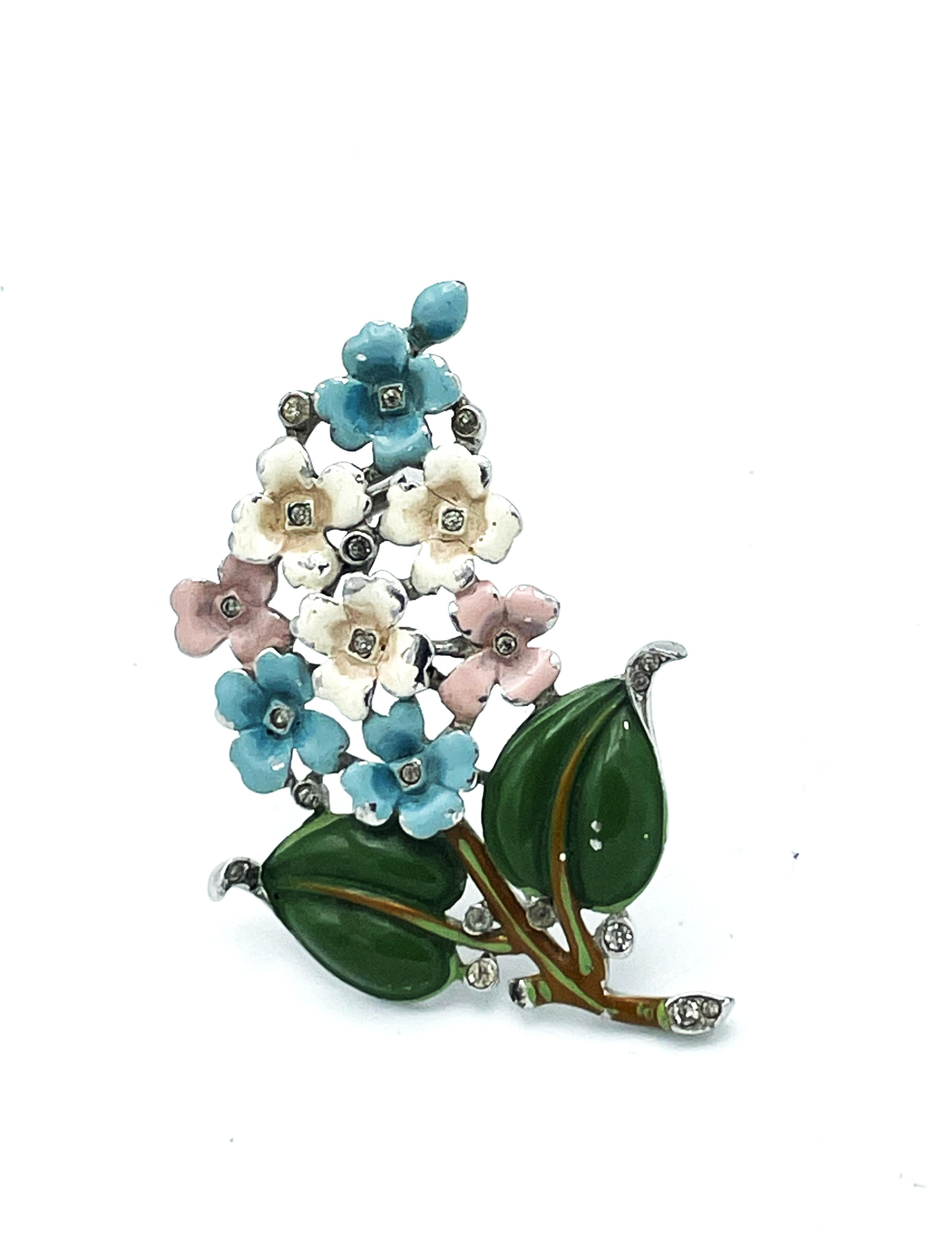 Flower booke pin/brooch by Trifari 1930/40er years USA. 
Rhodium-plated metal with enameled rosa and light blue flowers, green leaves decorated with small  rhinestones.  There is a small barb betweenthe 2 needles to secure the clip. 

Dimensions