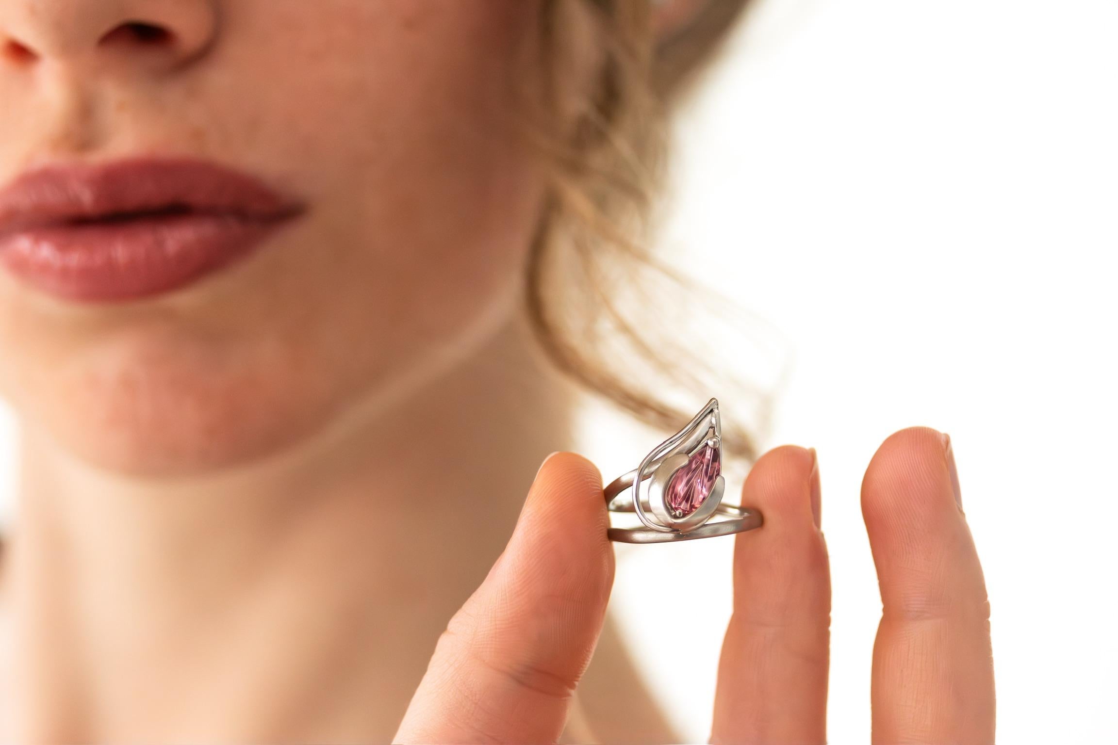 Una pieza hermosa y única que es cómoda de llevar y, a pesar del tamaño del tocado 
(11 mm x 7 mm), no requiere un ajuste alto. Parece un capullo de turmalina rosa que se abre hacia la punta del dedo.

Detalles:
Platino 950/-
Turmalina rosada 