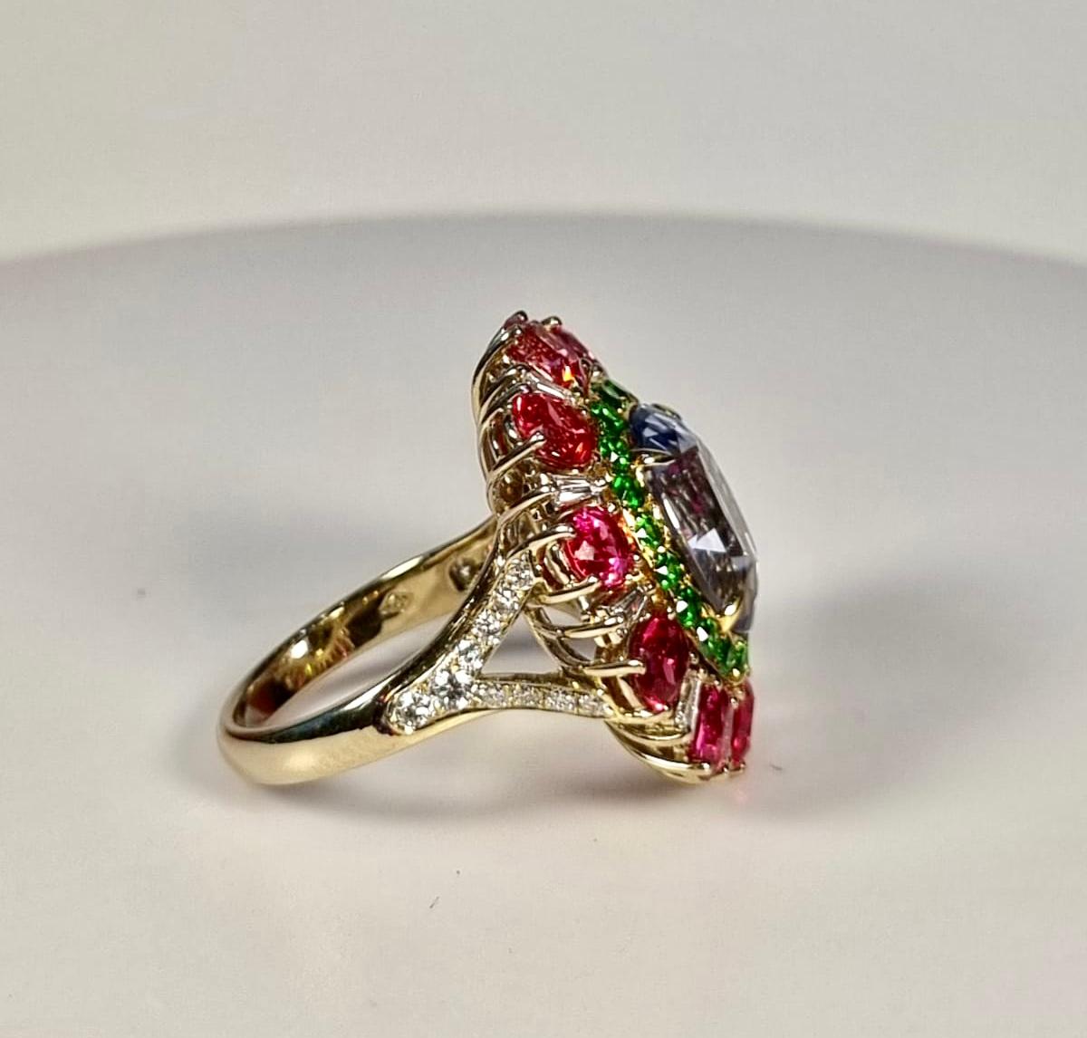 Flower ring with non heated  central Blue Sapphire Garnet and Spinels in 18k gold 
Not Heated central Sapphire  8.27 cts
20 green garnets  0.76 cts
10 pink spinels  4.46 cts
20 round diamonds  0.64 cts
Ring weight 10.88gr
Ring size Europe 55
Ring