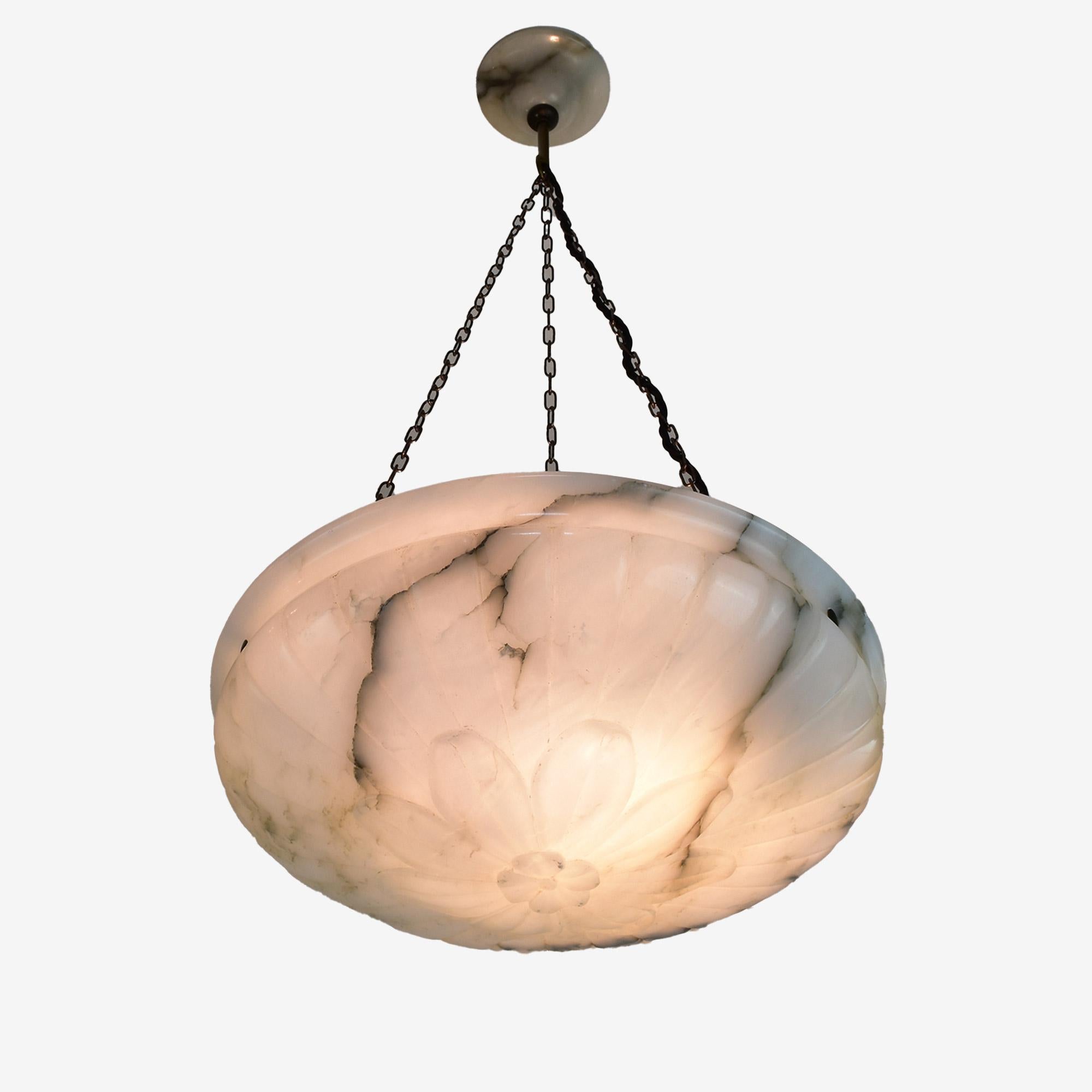 Un'elegante lampada da soffitto francese in alabastro Art Decor con una decorazione a forma di fiore intagliato e il suo baldacchino originale in alabastro.
Questa lampada è dotata di un attacco E27 ed è stata ricablata per il mercato europeo. Le