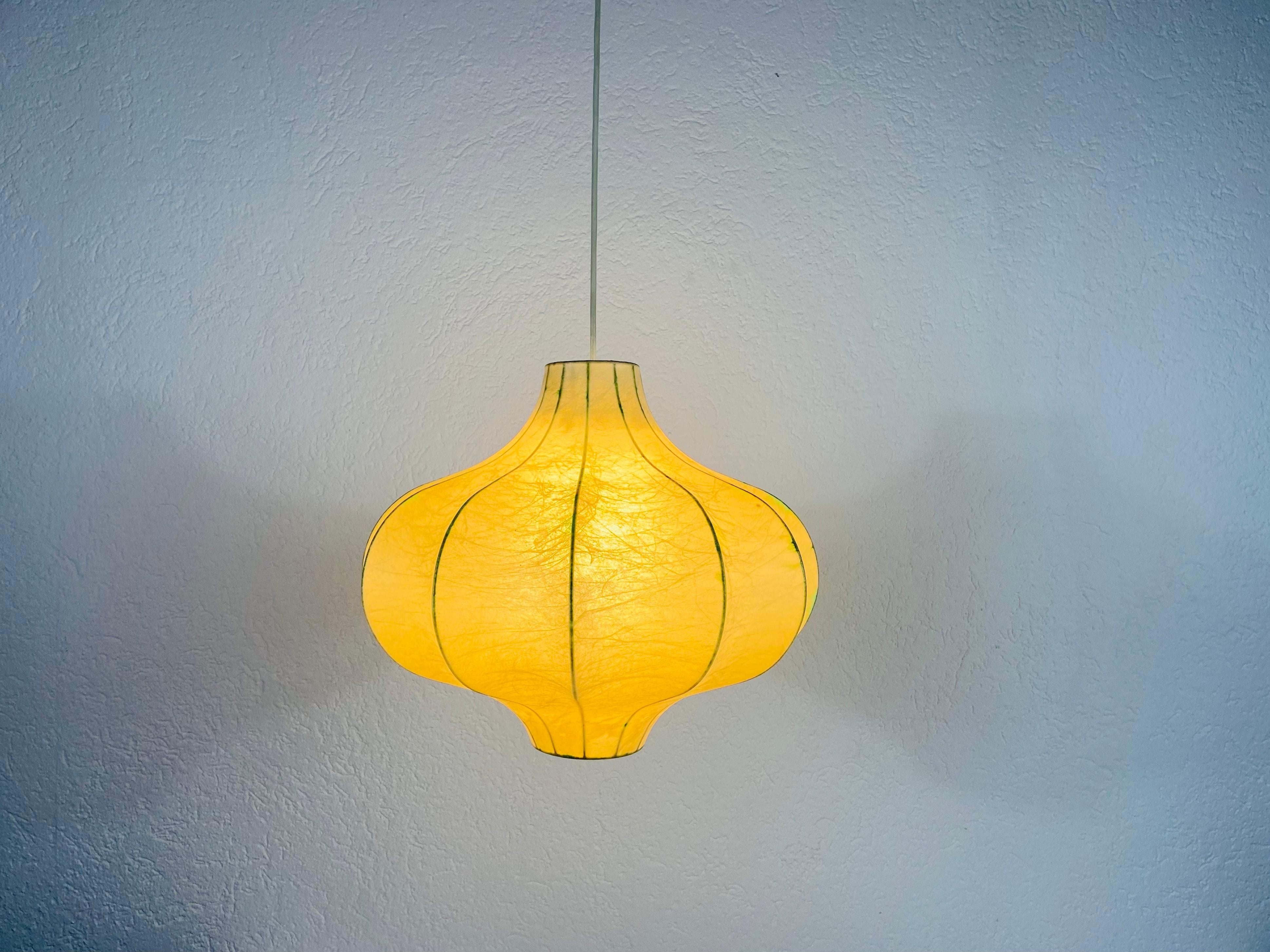 A cocoon pendant lamp made in Italy in the 1960s. The hanging lamp has been manufactured in the design of the lamps made by Achille Castiglioni. The lamp shade is of original cocoon and has a flower shape. 

Measures: Max height 91 cm
Height 35