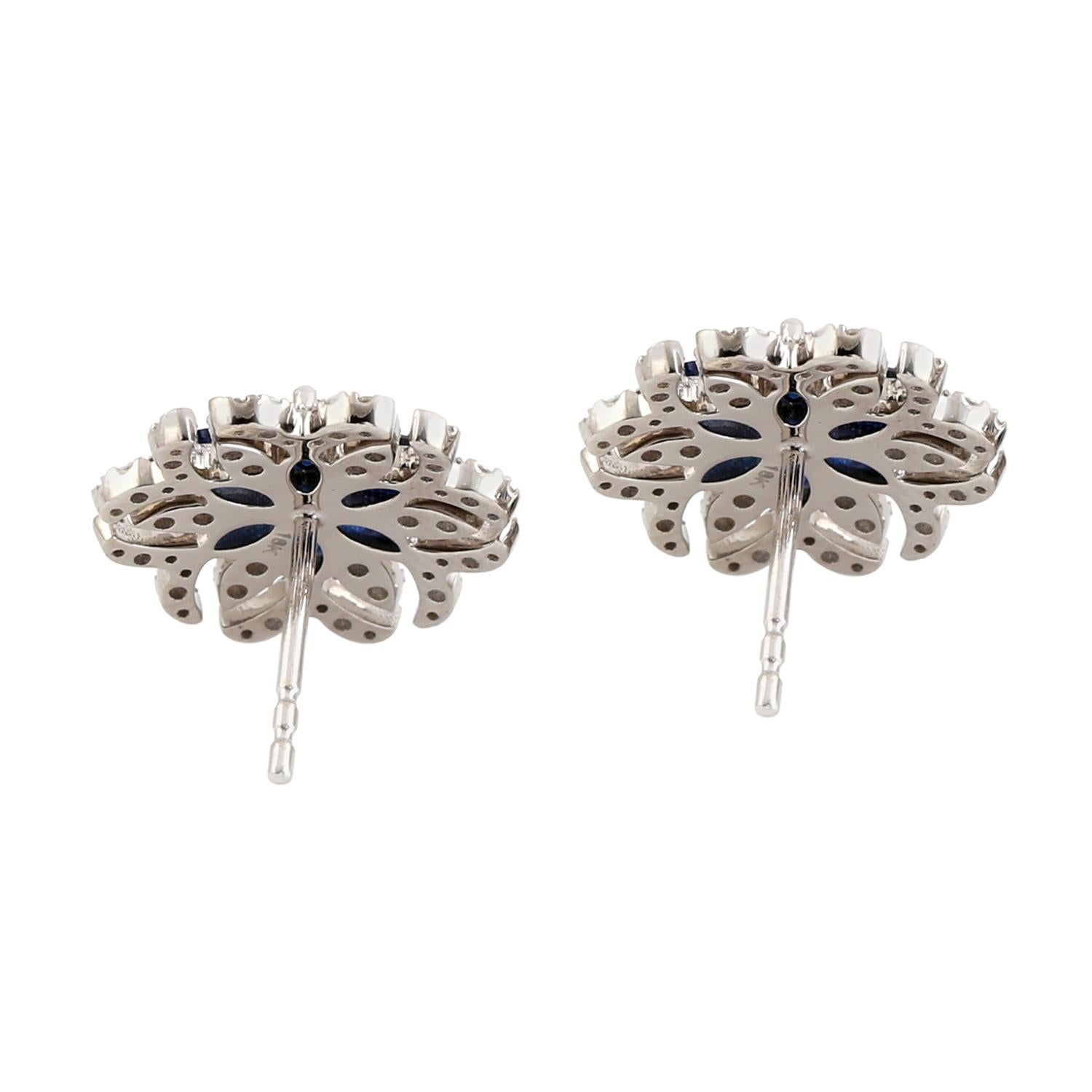 These earrings are designed in the shape of flowers and feature beautiful blue sapphires and diamonds set in 18k white gold. Surrounding the sapphires are sparkling diamonds, which add a touch of shine and glamour to the overall design. The white