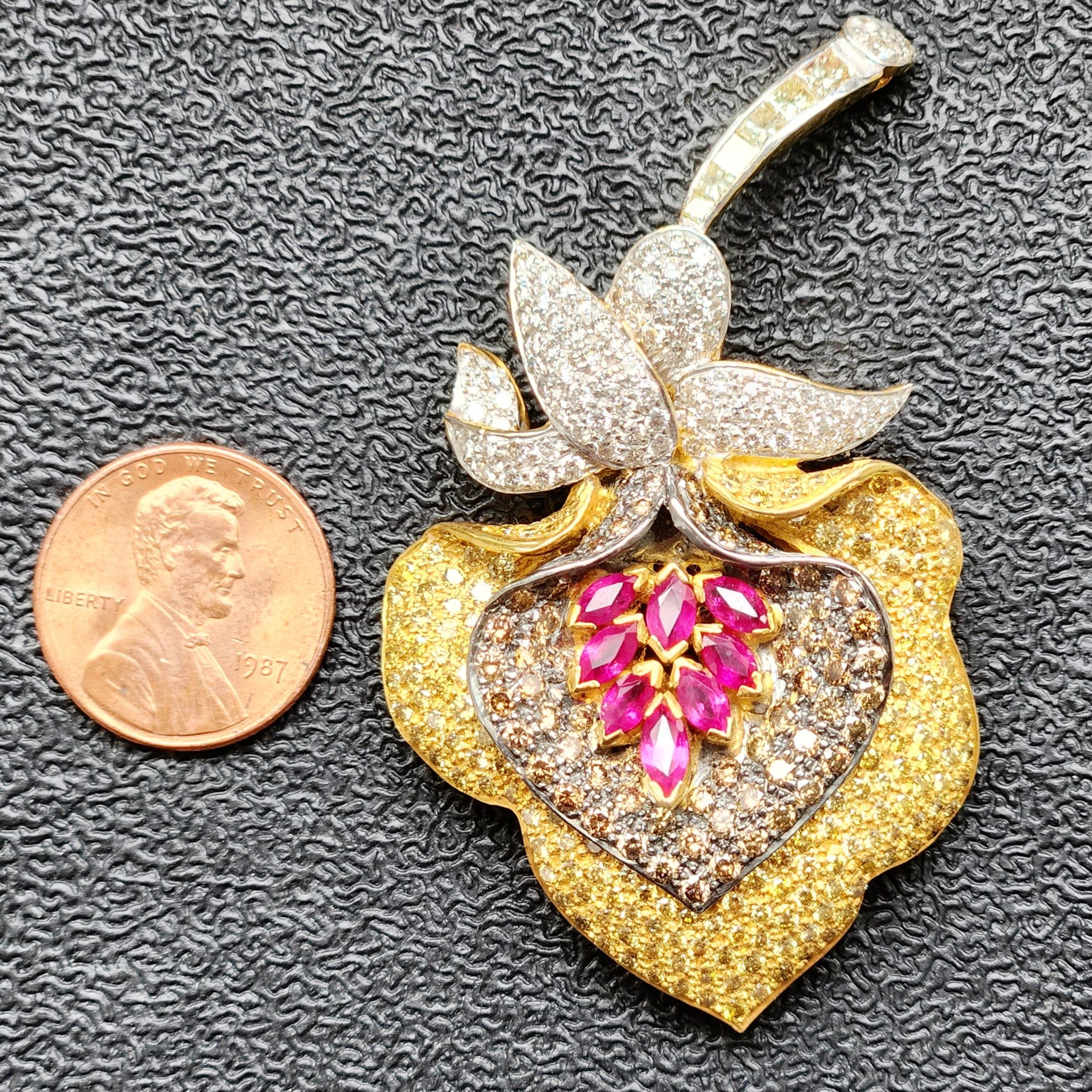 Die blumenförmige Multicolor-Diamantbrosche mit einem Gewicht von 20,8 Gramm ist ein atemberaubendes Schmuckstück, das Eleganz und Raffinesse ausstrahlt. Dieser Broschenanhänger aus 18 Karat Weiß- und Gelbgold zeigt in der Mitte einen roten,