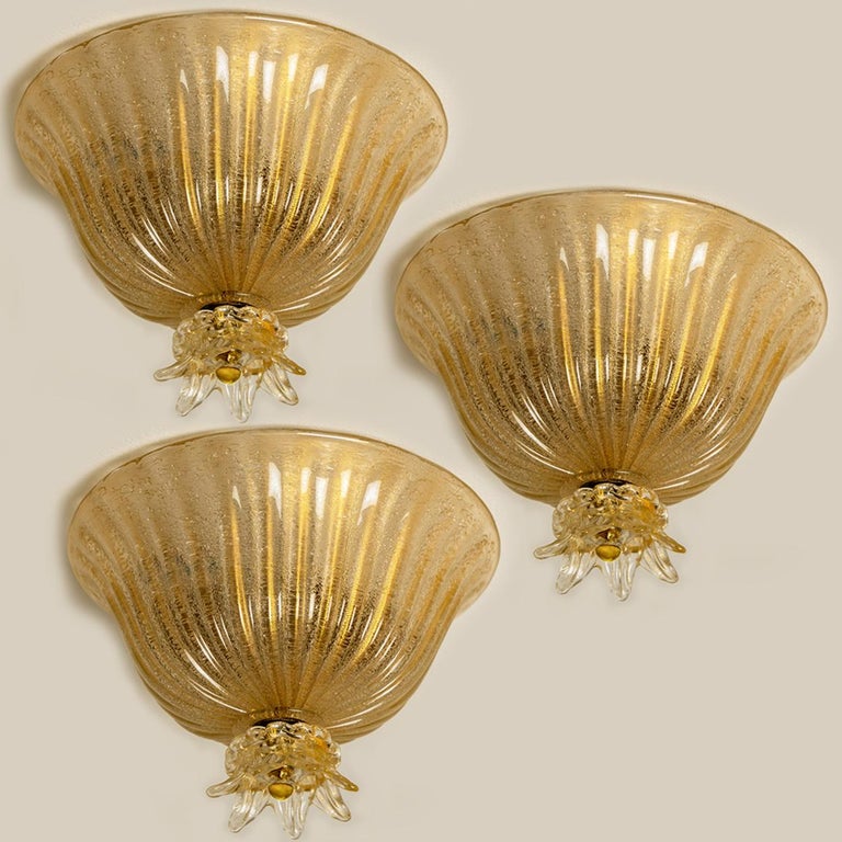 An elegant blown Murano glass flushmount by Barovier & Toso. The light fixture is made of thick Murano glass with gold details. Mounted on a white backplate. The lights refract light beautifully. The flush mount fills the room with a soft, warm and