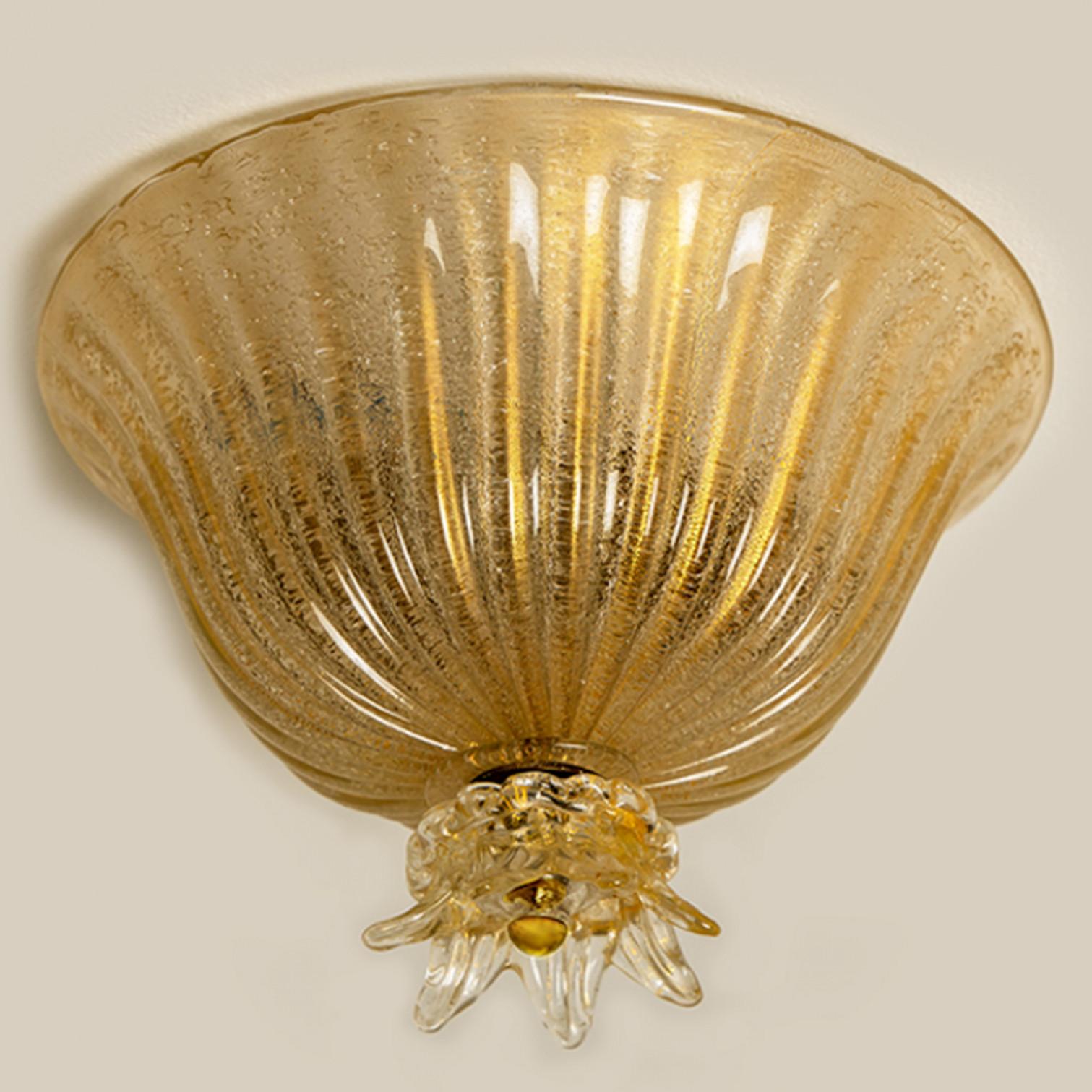 An elegant blown Murano glass flush mount by Barovier & Toso. The light fixture is made of thick Murano glass with gold details. Mounted on a white back plate. The lights refract light beautifully. The flush mount fills the room with a soft, warm