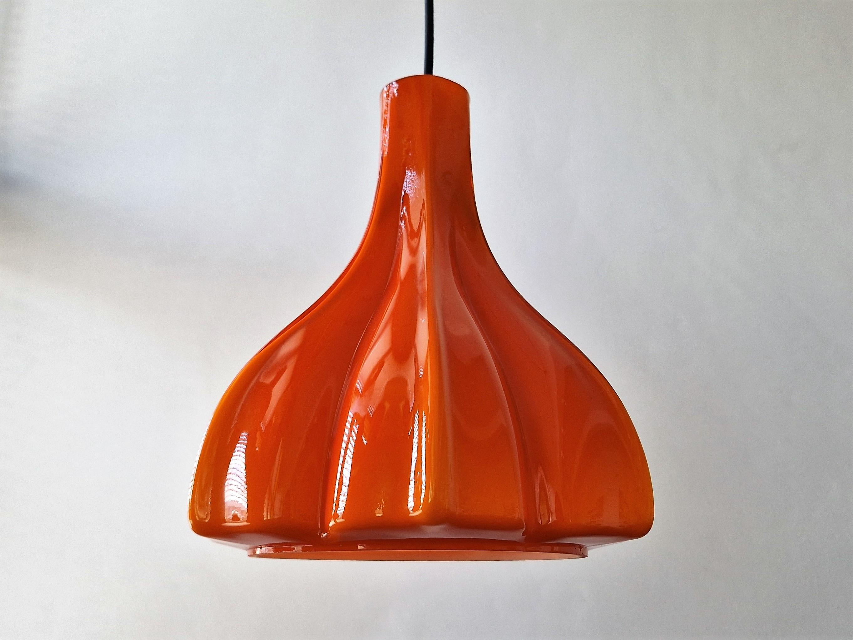 This beautiful flower shaped pendant lamp was made by the German manufacturer Peill & Putzler. It is made of double-layerd hand blown Murano glass with an orange outside and an opal white inside. When lit it creates a warm and atmospheric glow of