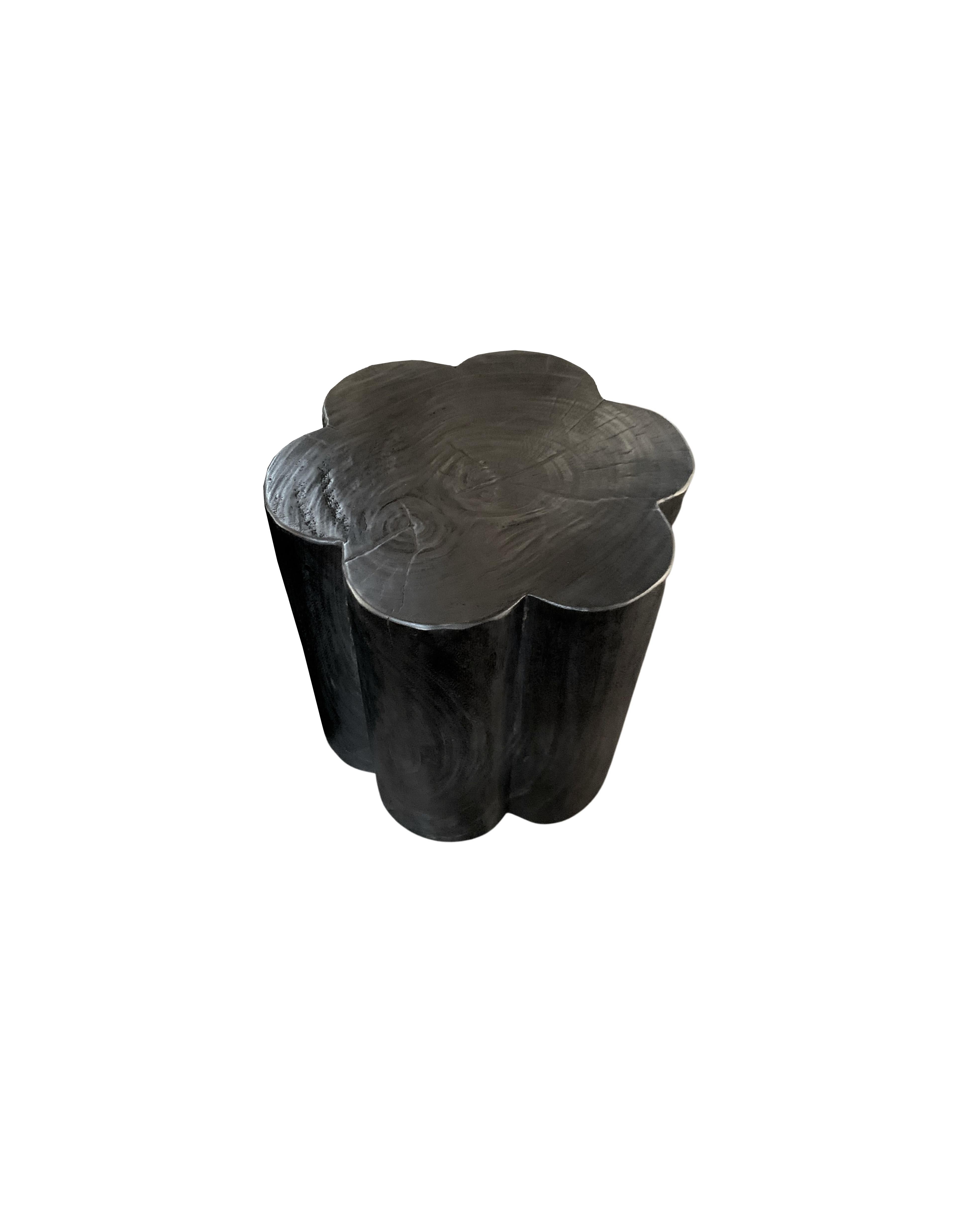 A wonderfully sculptural flower shaped side table. Its rich black pigment was achieved through burning the wood three times. Its neutral pigment and subtle wood texture makes it perfect for any space. A uniquely sculptural and versatile piece