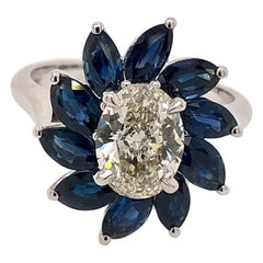 Flower Star Ring with a White Oval Diamond and Marquise Blue Sapphires