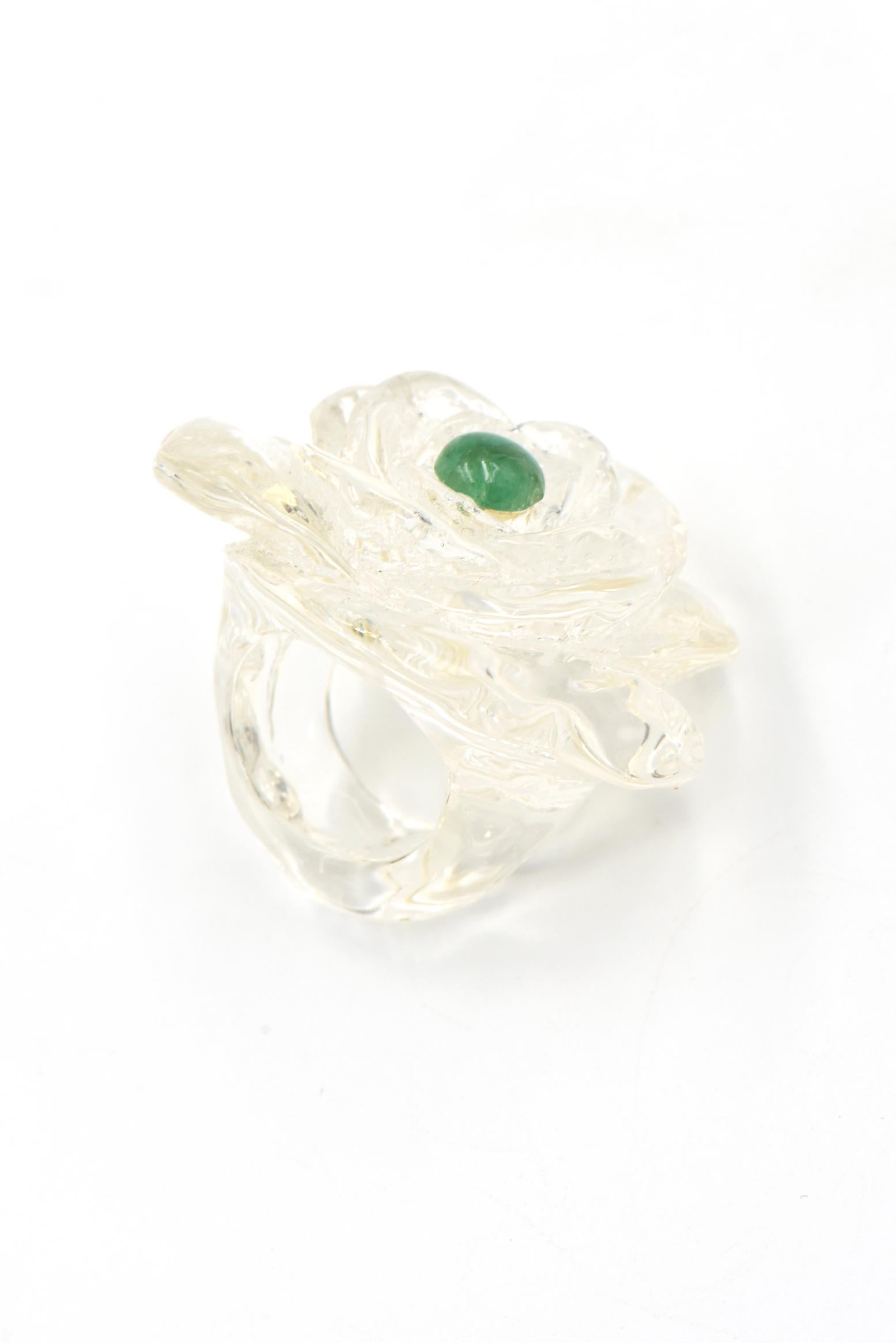 Clear acrylic flower ring presenting a emerald stone in the center. U.S. size: 7.5