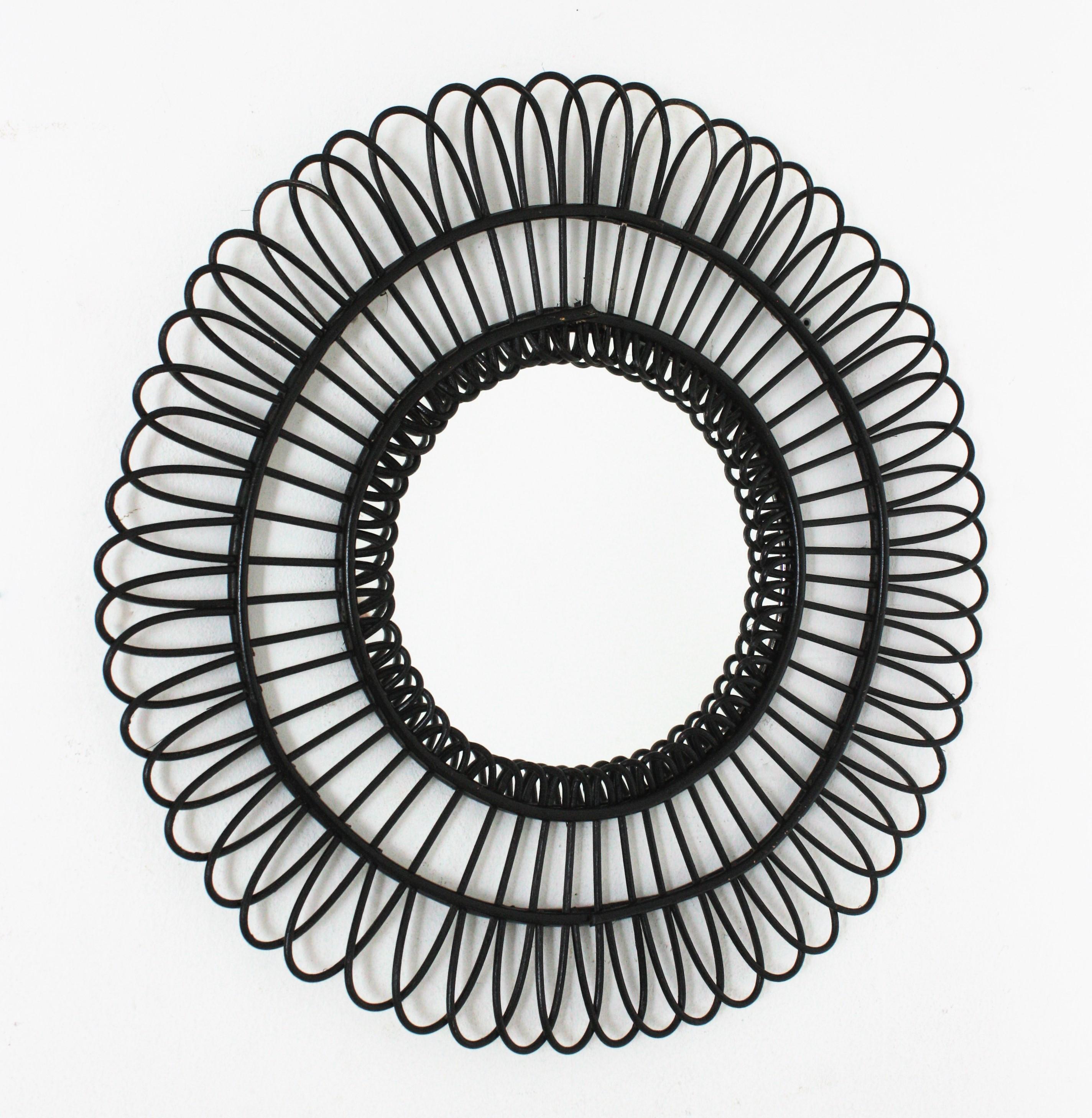 Black Mid-Century Modern rattan mirror, Spain 1960s.
This handcrafted mirror features a round rattan frame with rattan petals placed in sunburst or flower disposition.
This wall mirror would be a nice addition in a contemporary or classical
