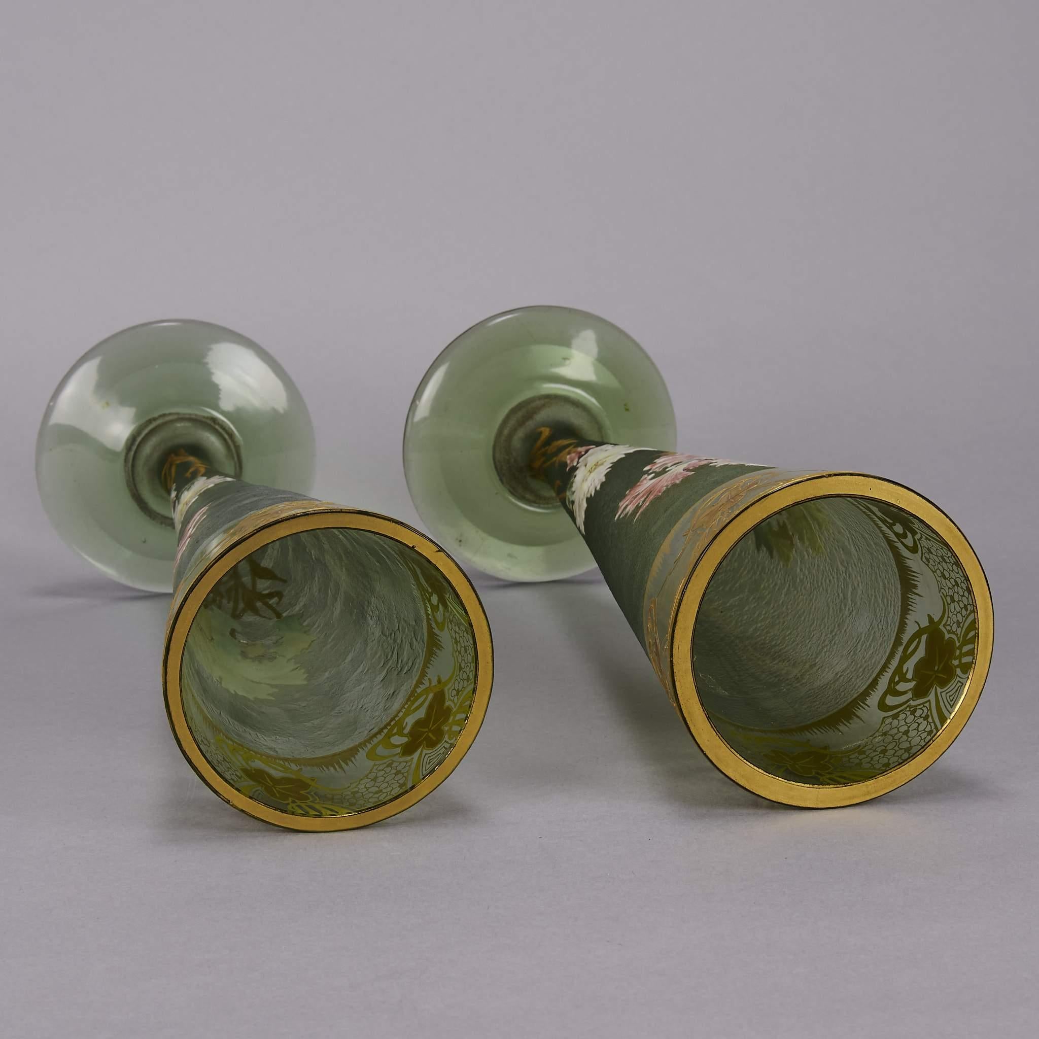 A stunning pair of decorative green glass vases of trumpet form enamel painted with white and pink flowers. The surface with excellent hand finished detail delicately decorated with gilded highlights to rim, signed Mont Joye L & Cie.

Mont Joye