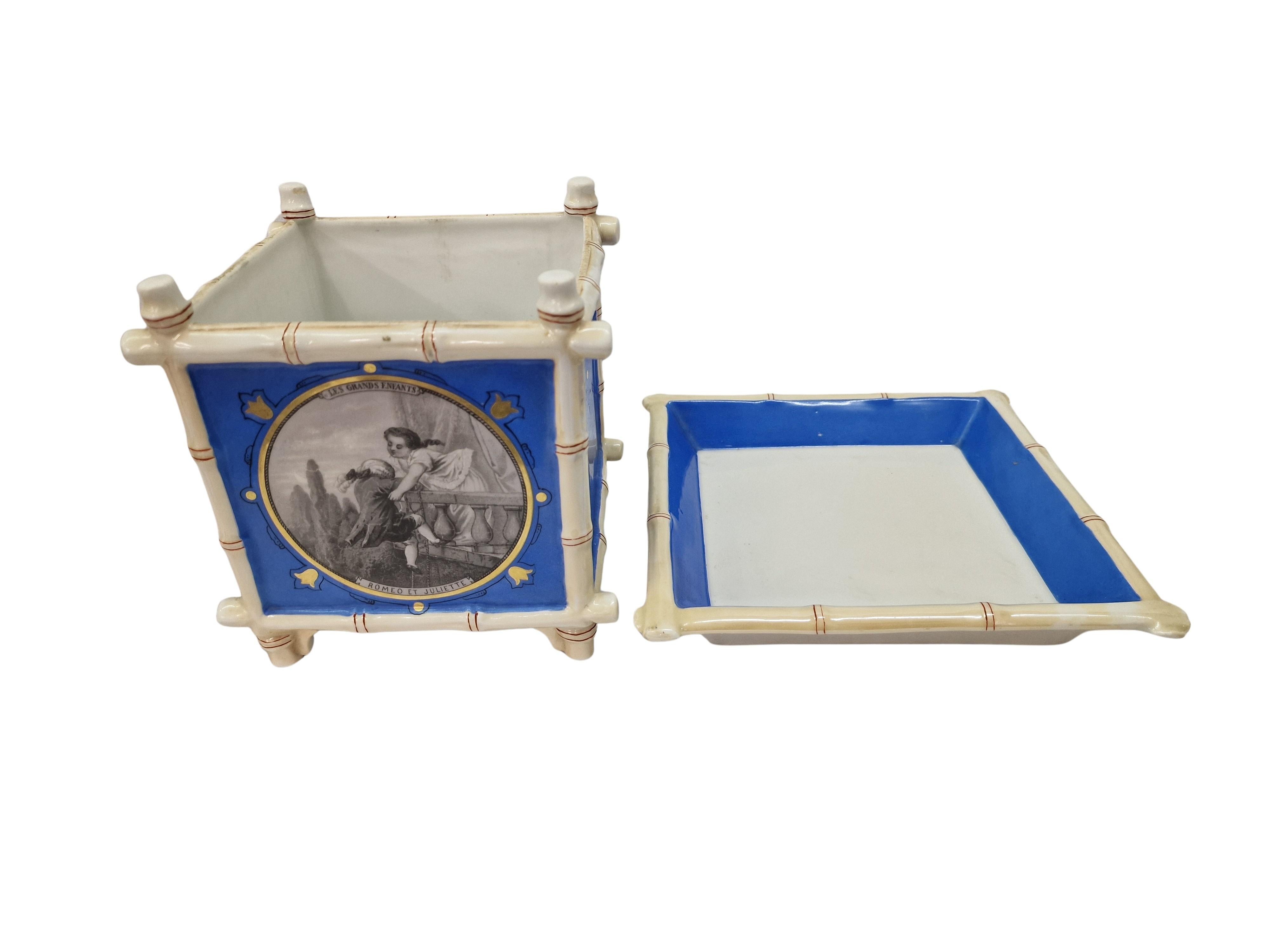 This flower pot was made by the German porcelain manufacturer Fischer und Mieg, Pirkenhammer, around 1900 – 1910. 

The charming object is a two piece flower pot, consisting of a square plate and the planter. Two sides of the planter are each