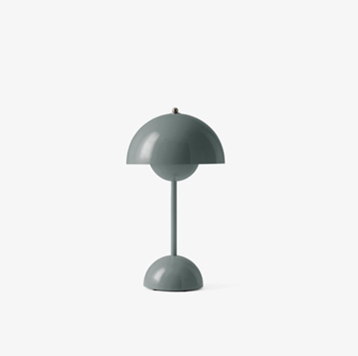 La lampe de table Flowerpot avec une suspension arrondie qui pend de l'abat-jour supérieur semi-dominé, design de Verner Panton 1968. 
Légèrement plus petite que la version lampe de table et délibérément légère, la VP9 portable est équipée d'un