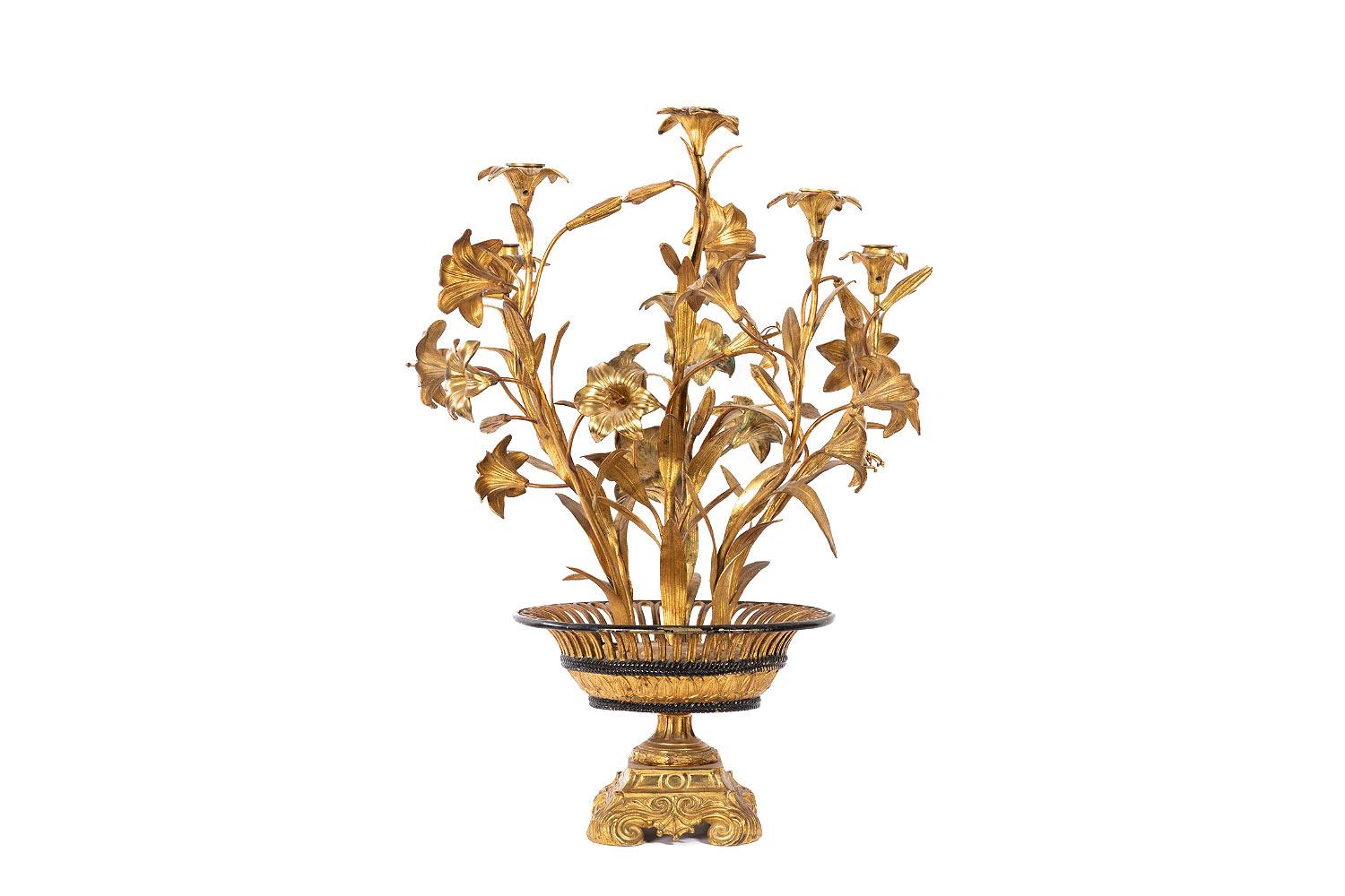 Six lights flowered candelabra in gilt brass and bronze representing a basket filled with flowers, standing on a four scrolled legs base topped by a piedouche supporting a gold and black patinated flared rim openwork basket, adorned with water