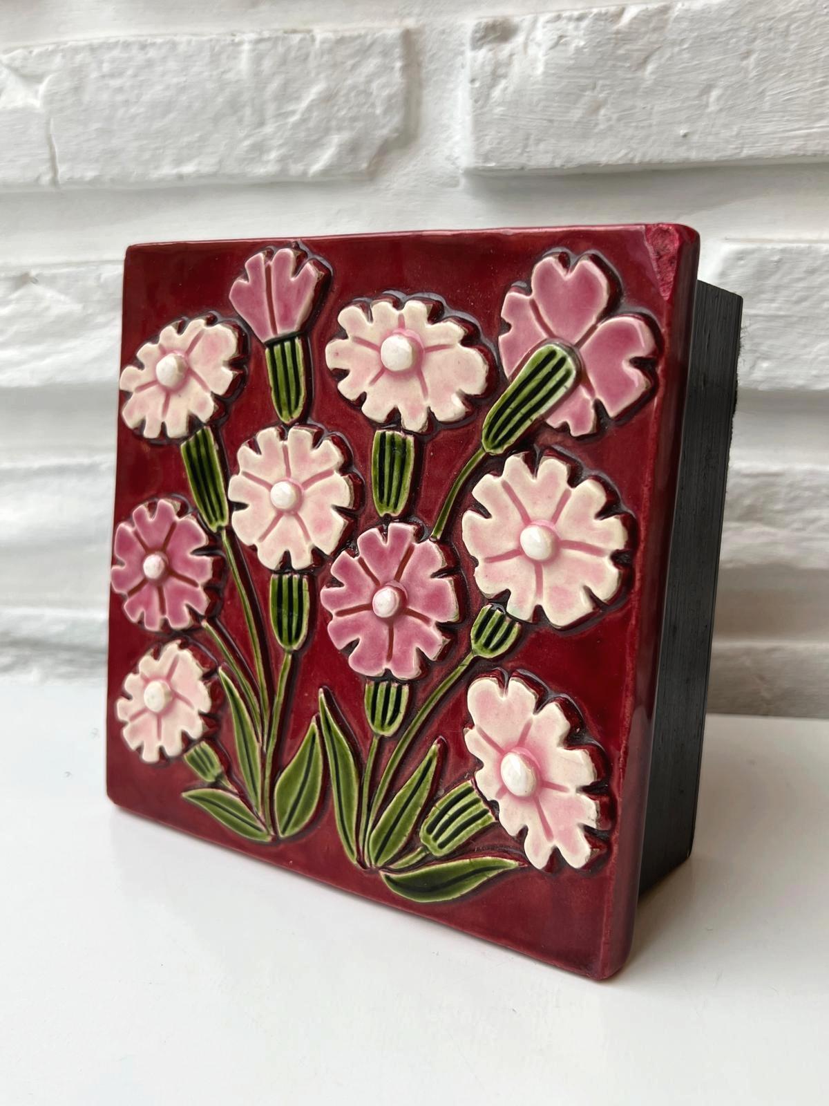 Schmuckkästchen aus glasierter Keramik mit Blumen und geschwärztem Holzsockel.

Dieses schöne Schmuckkästchen ist mit einem Deckel aus geprägtem Steingut versehen und mit einem floralen Emaille-Motiv verziert, das einen Nelkenstrauß zeigt. Die